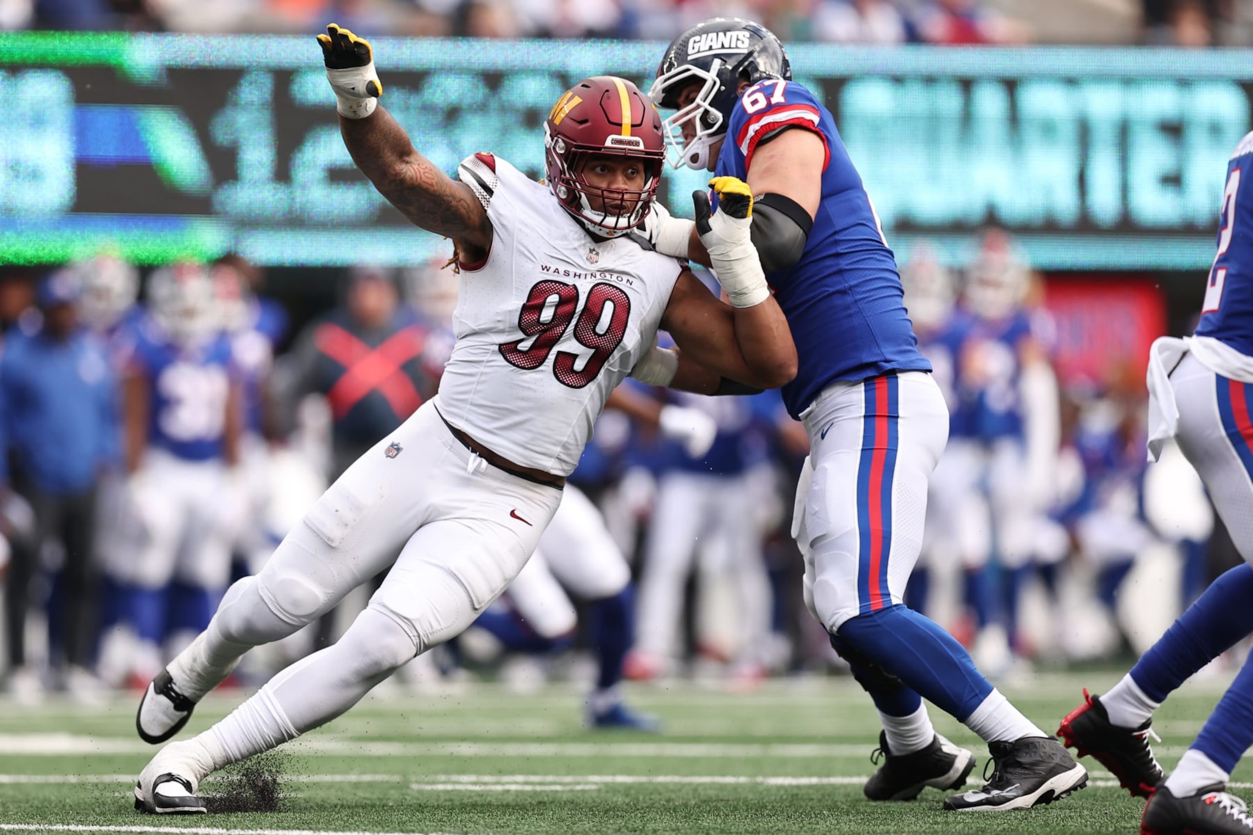 EAST RUTHERFORD, NEW JERSEY - OCTOBER 22: Wyatt Davis #67 of the New York Giants tackles Chase Young #99 of the Washington Commanders in the second half at MetLife Stadium on October 22, 2023 in East Rutherford, New Jersey. (Photo by Dustin Satloff/Getty Images)