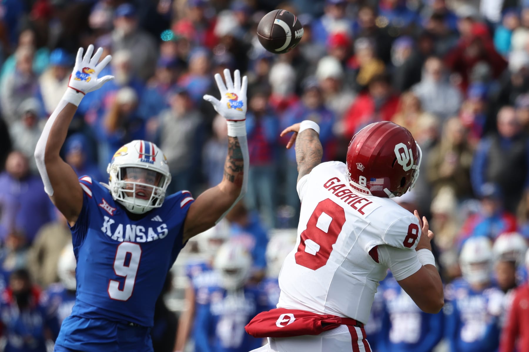 LAWRENCE, KS - OCTOBER 28: Kansas Jayhawks defensive lineman Austin Booker (9) leaps as Oklahoma Sooners quarterback Dillon Gabriel (8) throws a pass in the first quarter of a Big 12 football game between the Oklahoma Sooners and Kansas Jayhawks on Oct 28, 2023 at Memorial Stadium in Lawrence, KS.  (Photo by Scott Winters/Icon Sportswire via Getty Images)