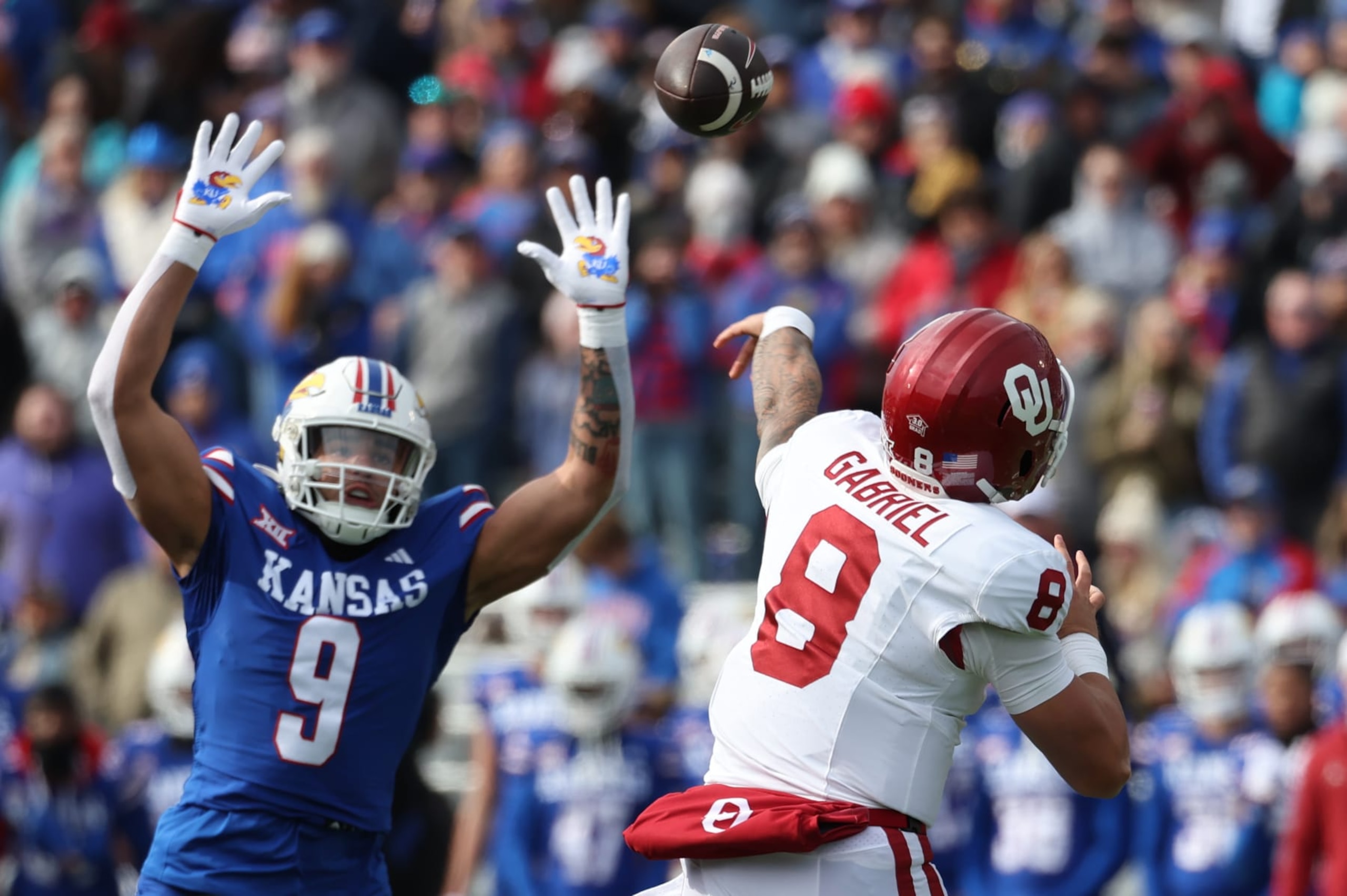 LAWRENCE, KS - OCTOBER 28: Kansas Jayhawks defensive lineman Austin Booker (9) leaps as Oklahoma Sooners quarterback Dillon Gabriel (8) throws a pass in the first quarter of a Big 12 football game between the Oklahoma Sooners and Kansas Jayhawks on Oct 28, 2023 at Memorial Stadium in Lawrence, KS.  (Photo by Scott Winters/Icon Sportswire via Getty Images)