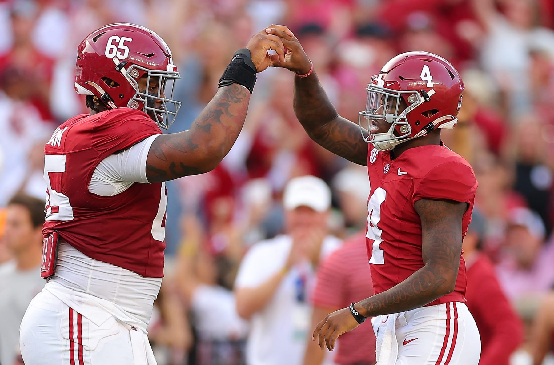 TUSCALOOSA, ALABAMA - OCTOBER 21:  Jalen Milroe #4 of the Alabama Crimson Tide reacts with JC Latham #65 after handing off for a rushing touchdown by Jase McClellan #2 against the Tennessee Volunteers during the third quarter at Bryant-Denny Stadium on October 21, 2023 in Tuscaloosa, Alabama. (Photo by Kevin C. Cox/Getty Images)