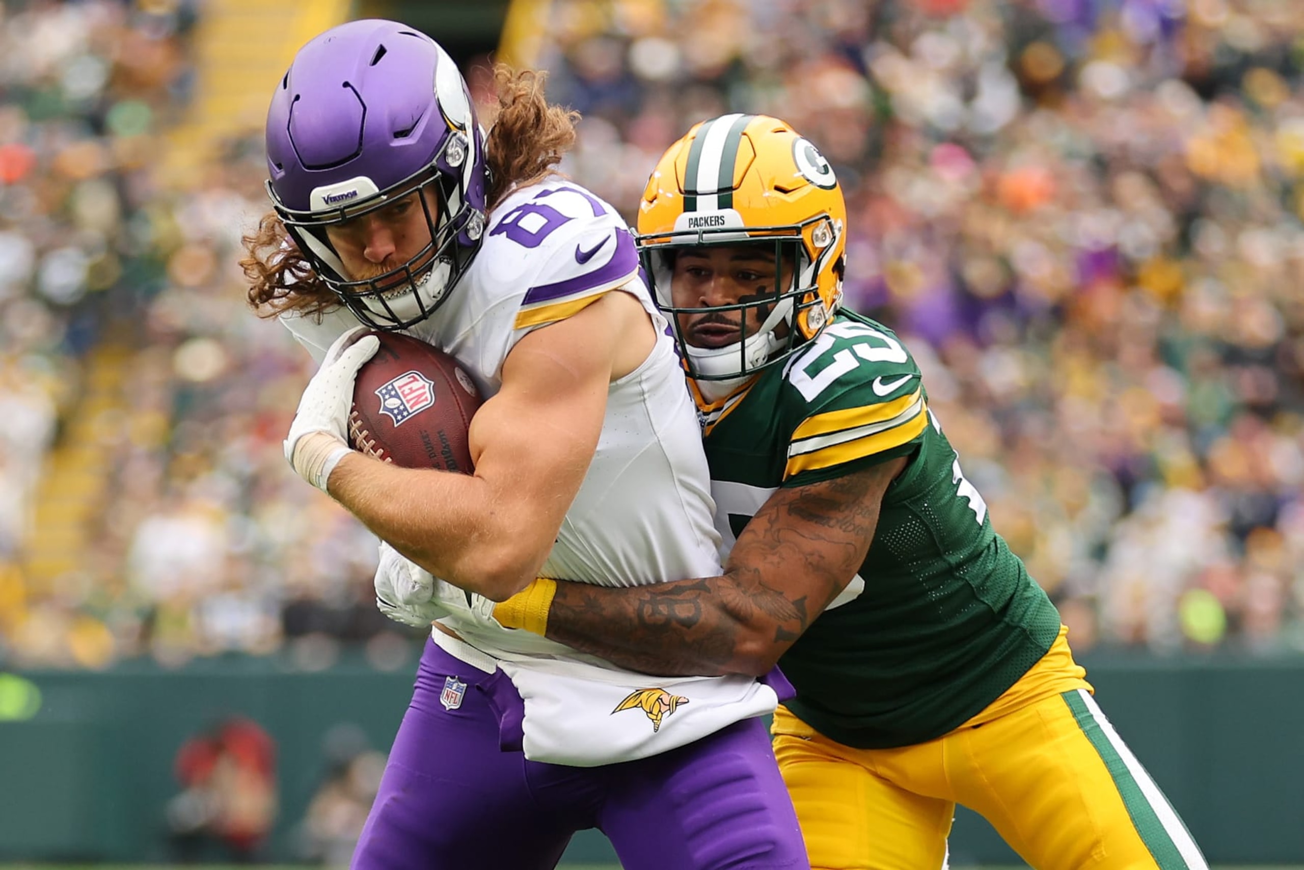 GREEN BAY, WISCONSIN - OCTOBER 29: Keisean Nixon #25 of the Green Bay Packers tackles T.J. Hockenson #87 of the Minnesota Vikings during the first quarter at Lambeau Field on October 29, 2023 in Green Bay, Wisconsin. (Photo by Michael Reaves/Getty Images)