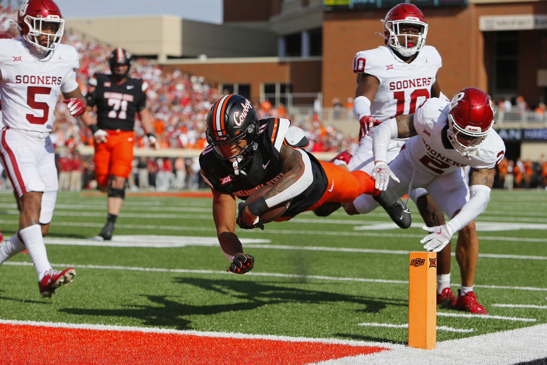 STILLWATER, OK - NOVEMBER 4:  Running back Ollie Gordon II #0 of the Oklahoma State Cowboys dives into the end zone on a 20-yard touchdown run against defensive back Billy Bowman Jr. #2 of the Oklahoma Sooners in the first quarter of Bedlam at Boone Pickens Stadium on November 4, 2023 in Stillwater, Oklahoma.  (Photo by Brian Bahr/Getty Images)