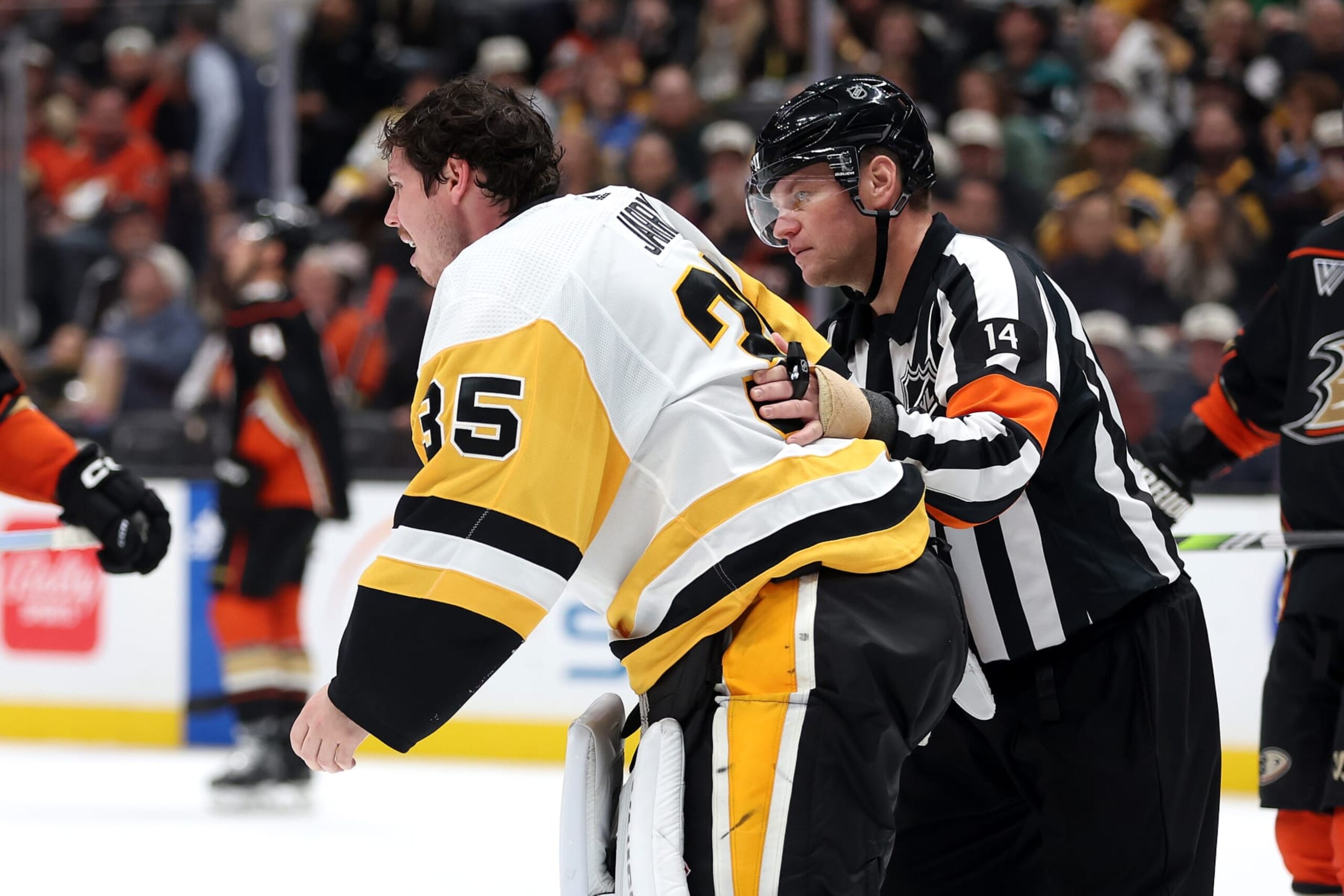 ANAHEIM, CALIFORNIA - NOVEMBER 07: Referee Trevor Hanson escorts Tristan Jarry #35 of the Pittsburgh Penguins off the ice after an injury during the second period of a game against the Anaheim Ducks at Honda Center on November 07, 2023 in Anaheim, California. (Photo by Sean M. Haffey/Getty Images)