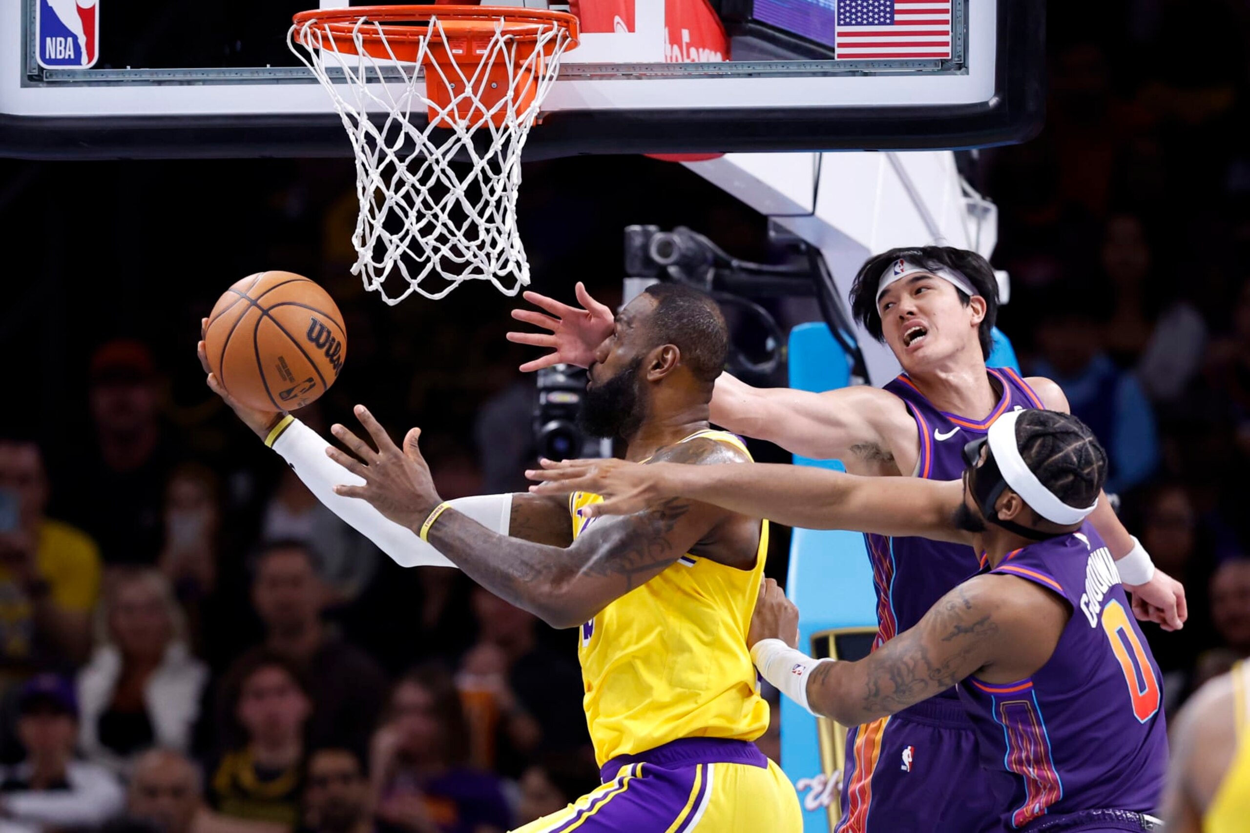 PHOENIX, ARIZONA - NOVEMBER 10: LeBron James #23 of the Los Angeles Lakers attempts a layup against Yuta Watanabe #18 of the Phoenix Suns and Jordan Goodwin #0 during the first half of the NBA In-Season Tournament game at Footprint Center on November 10, 2023 in Phoenix, Arizona. NOTE TO USER: User expressly acknowledges and agrees that, by downloading and or using this photograph, User is consenting to the terms and conditions of the Getty Images License Agreement. (Photo by Chris Coduto/Getty Images)
