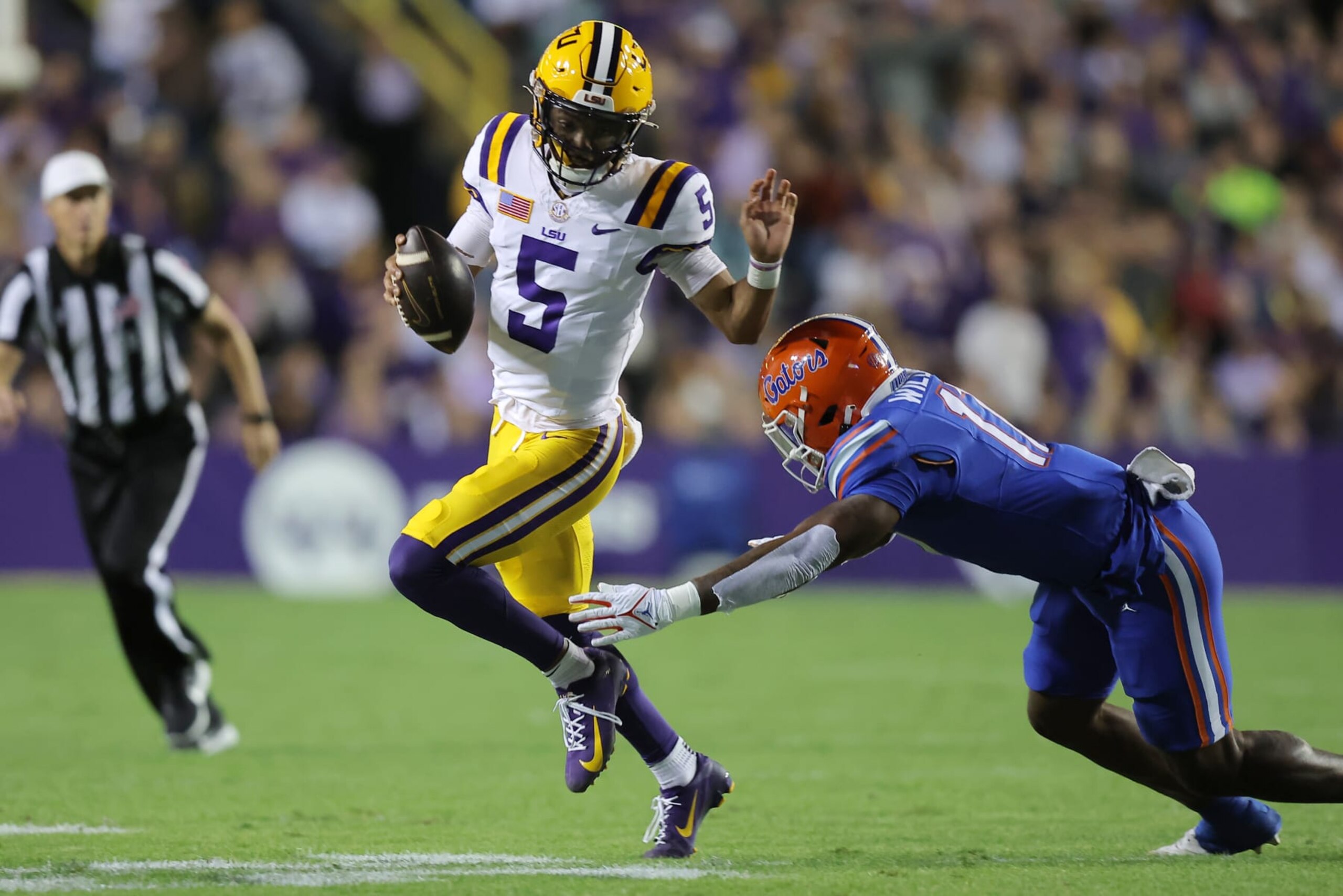 BATON ROUGE, LOUISIANA - NOVEMBER 11: Jayden Daniels #5 of the LSU Tigers runs with the ball as Scooby Williams #17 of the Florida Gators defends during the first half at Tiger Stadium on November 11, 2023 in Baton Rouge, Louisiana. (Photo by Jonathan Bachman/Getty Images)
