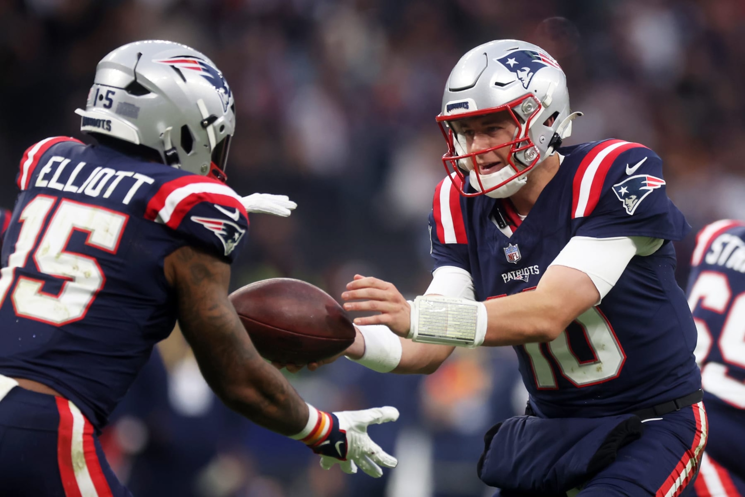 FRANKFURT AM MAIN, GERMANY - NOVEMBER 12: Mac Jones #10 of the New England Patriots hands off to Ezekiel Elliott #15 of the New England Patriots in the second quarter during the NFL match between the Indianapolis Colts and the New England Patriots at Deutsche Bank Park on November 12, 2023 in Frankfurt am Main, Germany. (Photo by Alex Grimm/Getty Images)