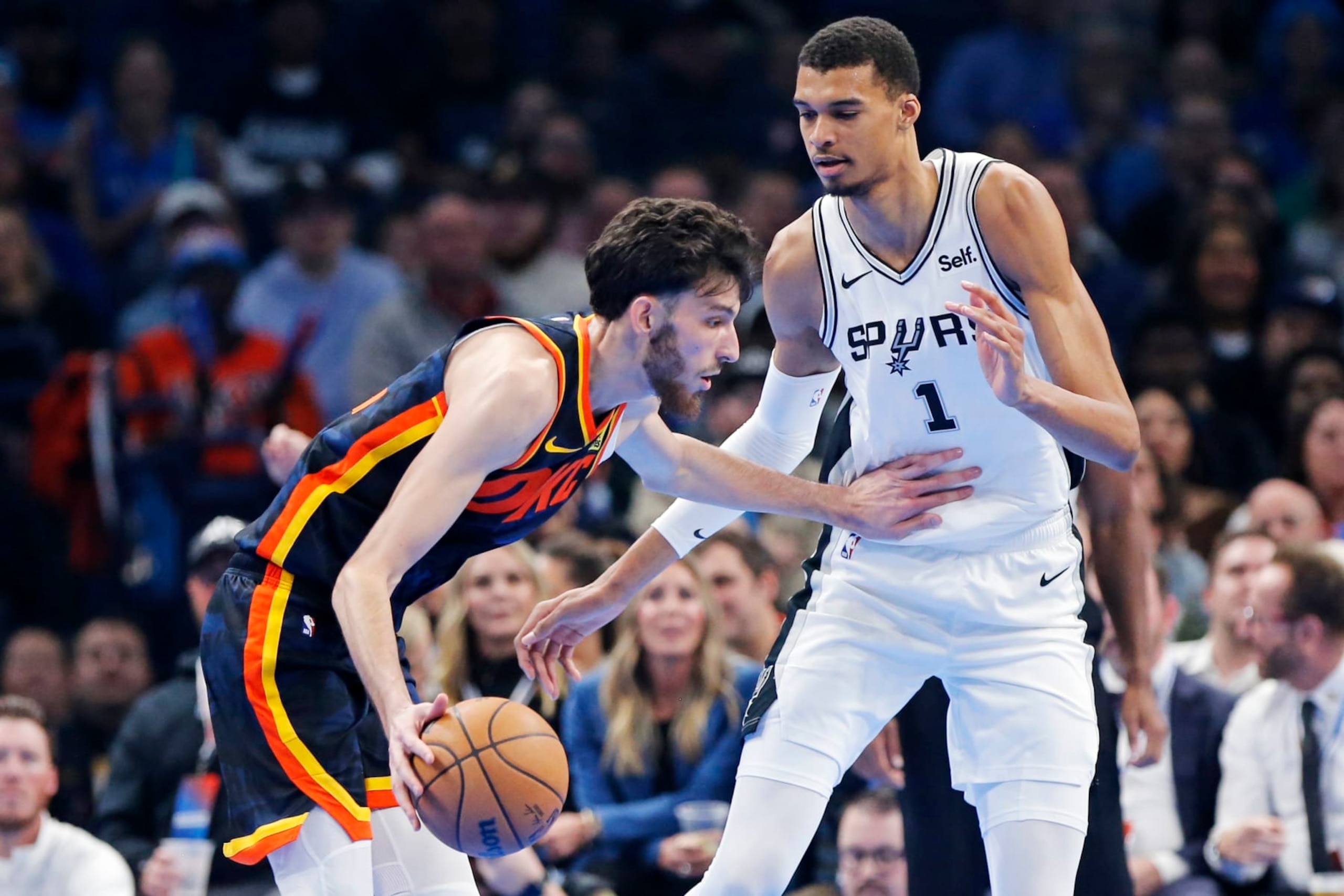 Oklahoma City forward Chet Holmgren, left, dribbles as San Antonio center Victor Wembanyama (1) defends during the first half of an NBA in-season tournament basketball game Tuesday, Nov. 14, 2023, in Oklahoma City. (AP Photo/Nate Billings)