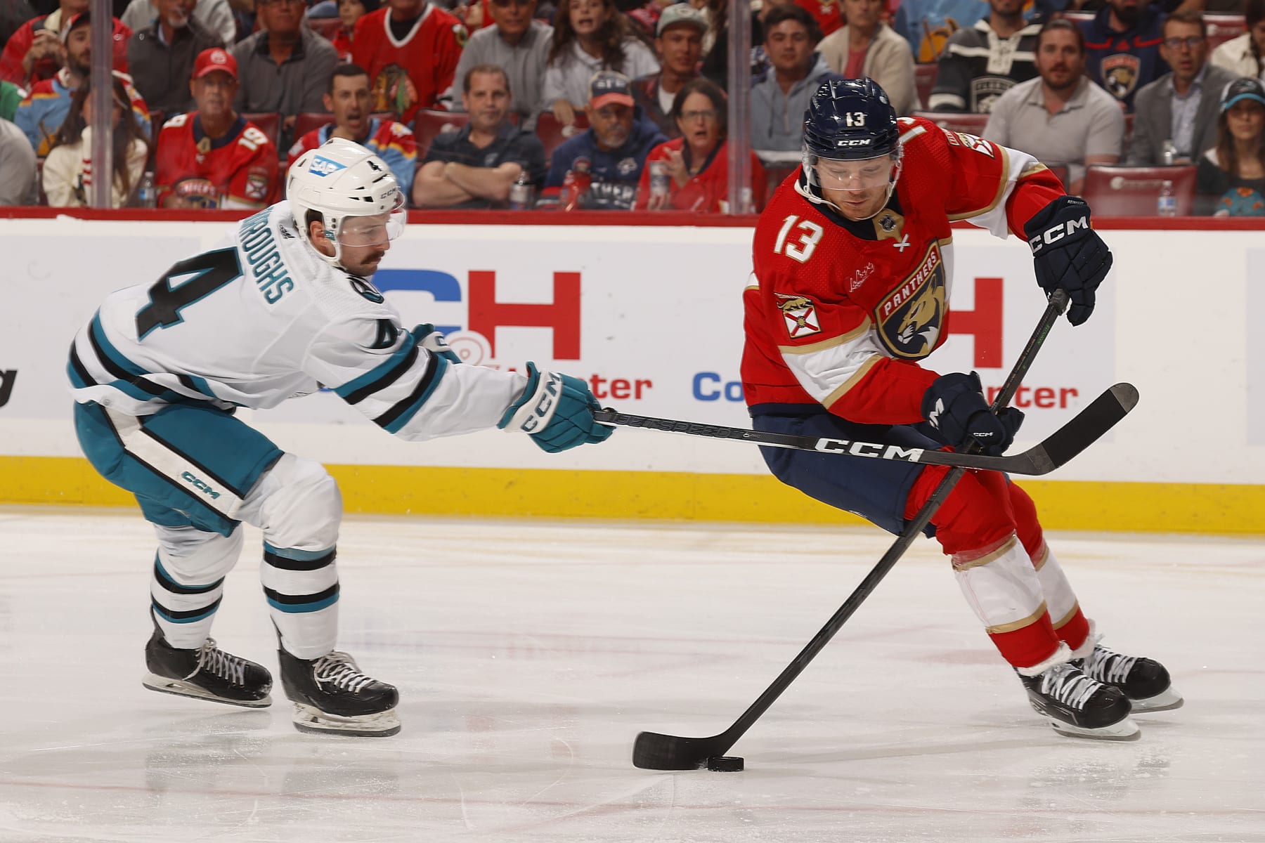 SUNRISE, FLORIDA - OCTOBER 24: Kyle Burroughs #4 of the San Jose Sharks crosses sticks with Sam Reinhart #13 of the Florida Panthers at the Amerant Bank Arena on October 24, 2023 in Sunrise, Florida. (Photo by Eliot J. Schechter/NHLI via Getty Images)