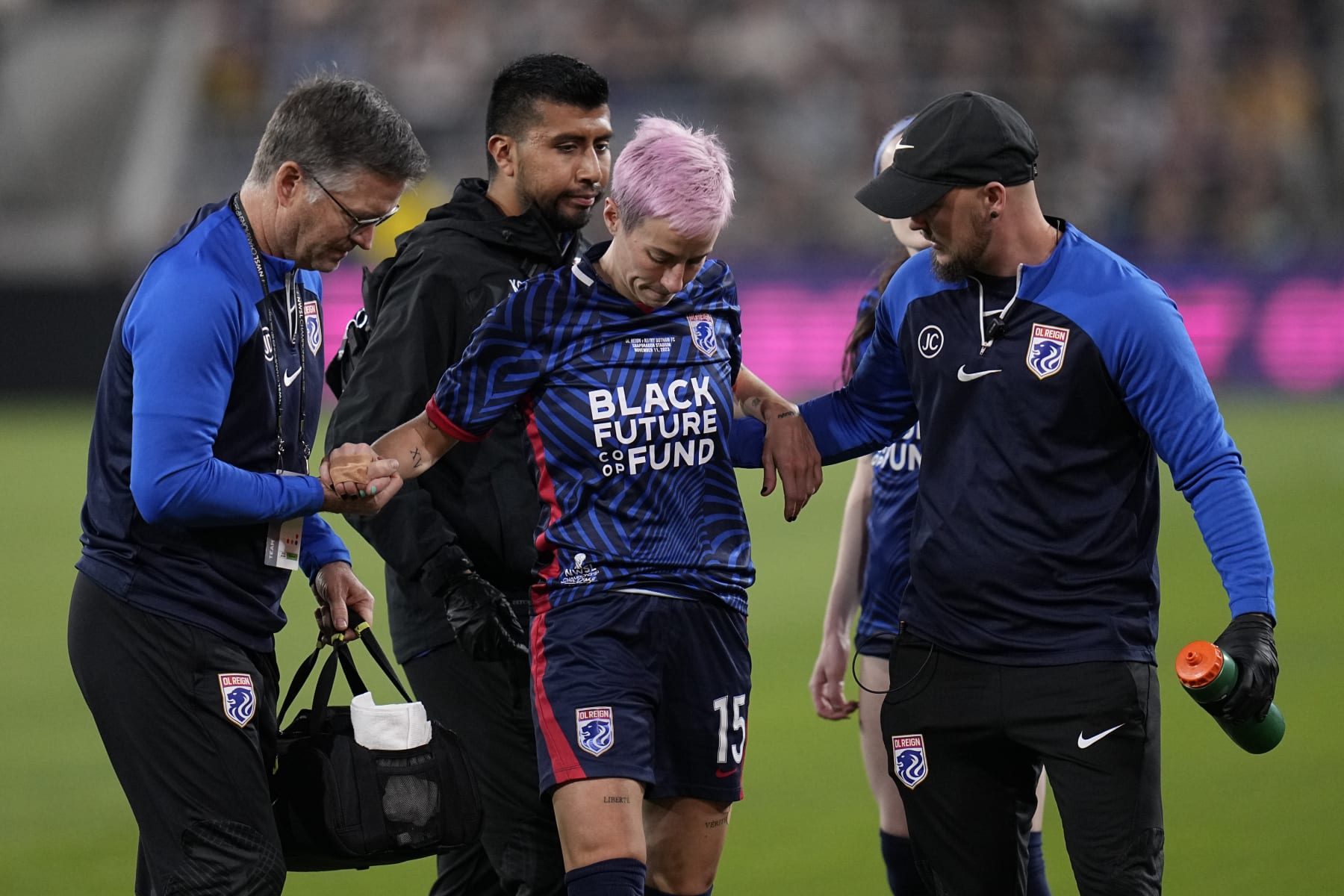 OL Reign forward Megan Rapinoe is helped up by team officials after an injury during the first half of the NWSL Championship soccer game against NJ/NY Gotham, Saturday, Nov. 11, 2023, in San Diego. (AP Photo/Gregory Bull)