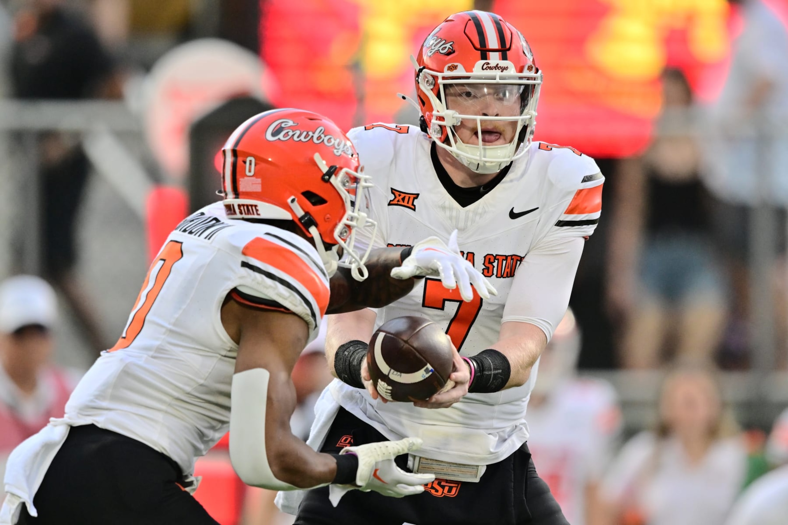 ORLANDO, FLORIDA - NOVEMBER 11: Alan Bowman #7 hands the ball off to Ollie Gordon II #0 of the Oklahoma State Cowboys in the first quarter against the UCF Knights at FBC Mortgage Stadium on November 11, 2023 in Orlando, Florida. (Photo by Julio Aguilar/Getty Images) ORLANDO, FLORIDA - NOVEMBER 11: Alan Bowman #7 hands the ball off to Ollie Gordon II #0 of the Oklahoma State Cowboys in the first quarter against the UCF Knights at FBC Mortgage Stadium on November 11, 2023 in Orlando, Florida. (Photo by Julio Aguilar/Getty Images)