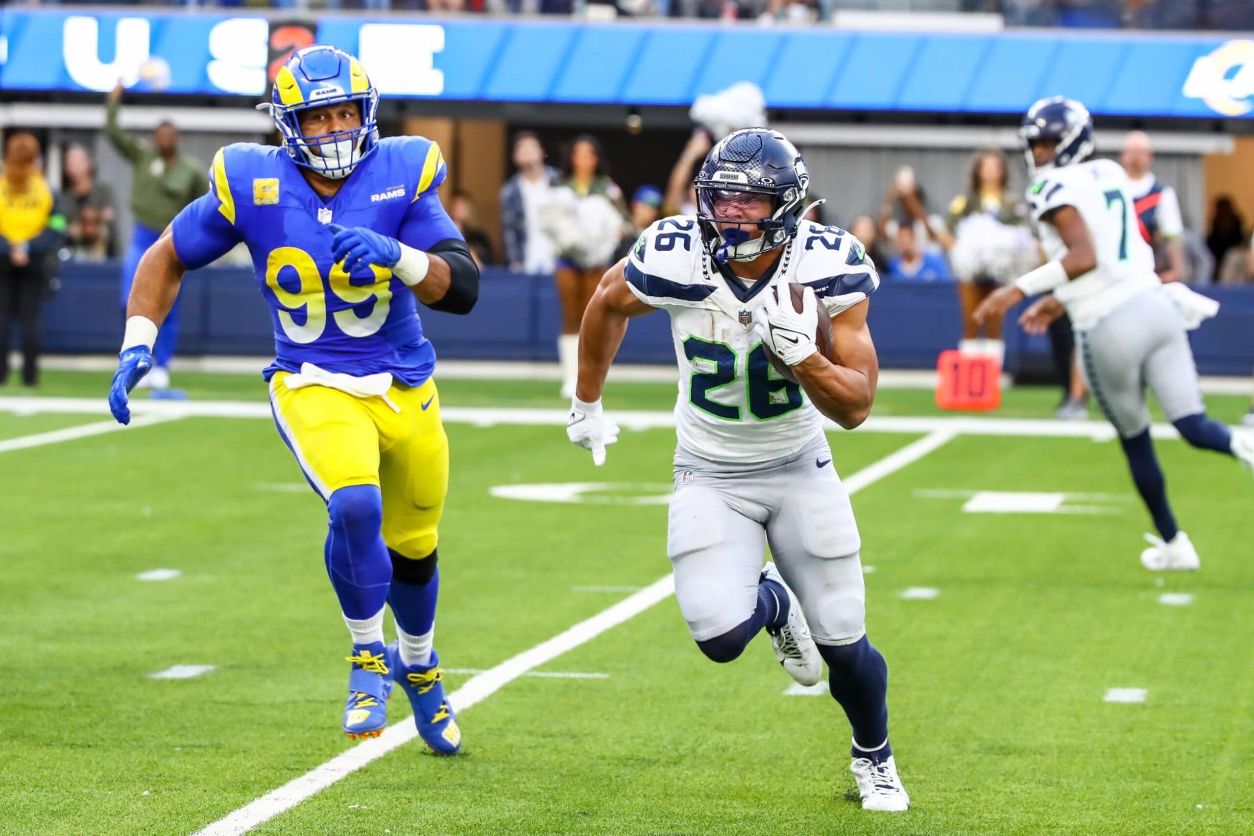 INGLEWOOD, CA - NOVEMBER 19: Seattle Seahawks running back Zach Charbonnet (26) runs away from Los Angeles Rams defensive tackle Aaron Donald (99) during the Seattle Seahawks vs Los Angeles Rams game on November 19, 2023, at SoFi Stadium in Inglewood, CA. (Photo by Jevone Moore/Icon Sportswire via Getty Images)