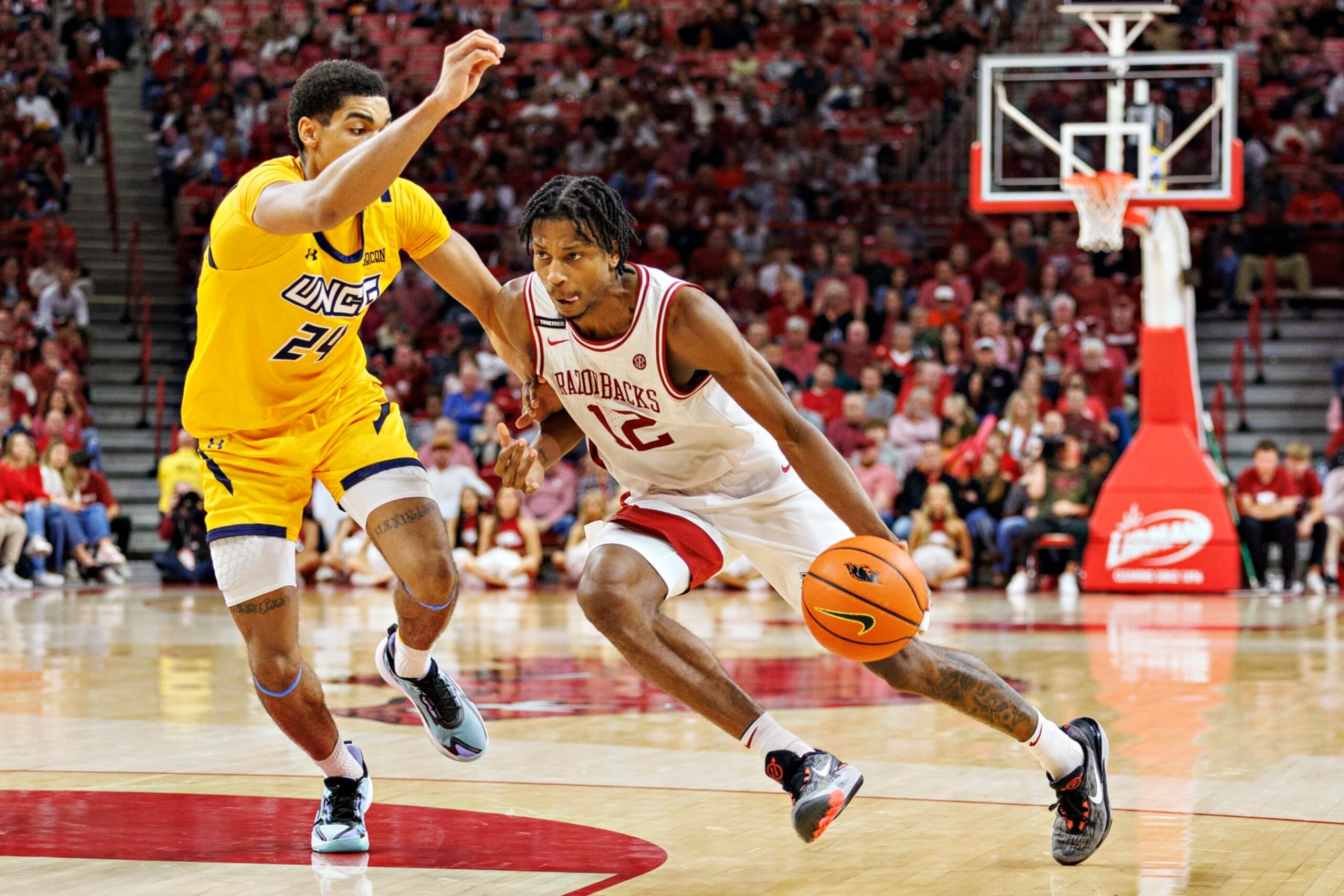 FAYETTEVILLE, ARKANSAS - NOVEMBER 17:  Tramon Mark #12 of the Arkansas Razorbacks drives to the basket against Tim Ceaser #24 of the UNC Greensboro Spartans at Bud Walton Arena on November 17, 2023 in Fayetteville, Arkansas. The Spartans defeated the Razorbacks 78-72.  (Photo by Wesley Hitt/Getty Images)