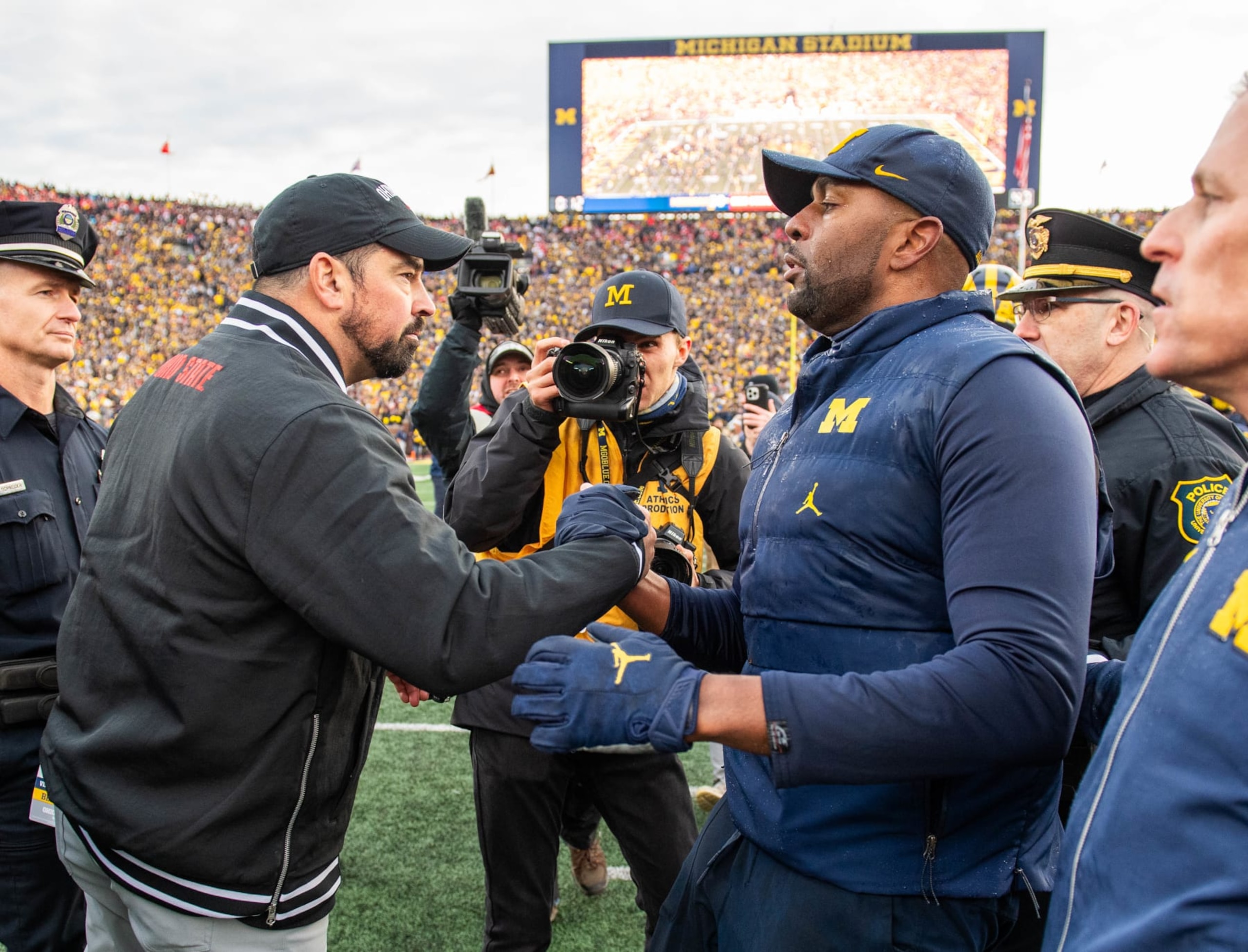 ANN ARBOR, MICHIGAN - NOVEMBER 25: Head Football Coaches Ryan Day (L) of the Ohio State Buckeyes and Sherrone Moore (R) of the Michigan Wolverines shake hands after a college football game at Michigan Stadium on November 25, 2023 in Ann Arbor, Michigan. The Michigan Wolverines won the game 30-24 to win the Big Ten East. (Photo by Aaron J. Thornton/Getty Images)