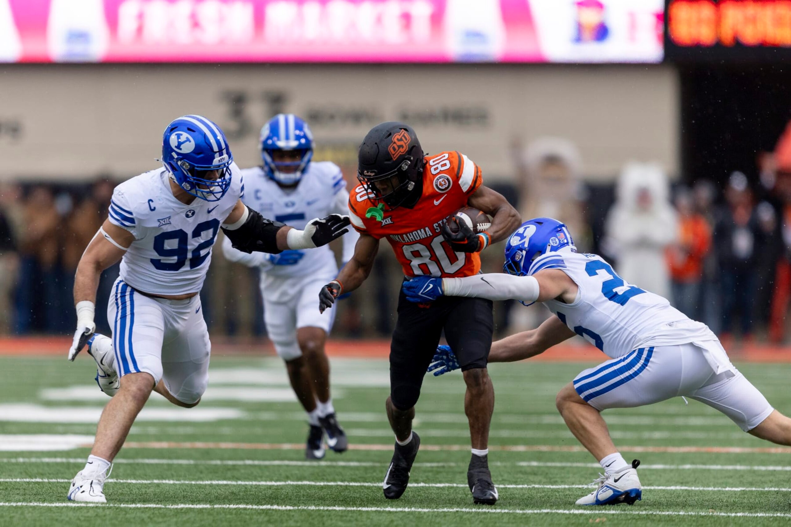 BYU safety Talan Alfrey (25) and defensive end Tyler Batty (92) tackle Oklahoma State wide receiver Brennan Presley (80) in the first half of an NCAA college football game Saturday, Nov. 25, 2023, in Stillwater, Okla. (AP Photo/Mitch Alcala)