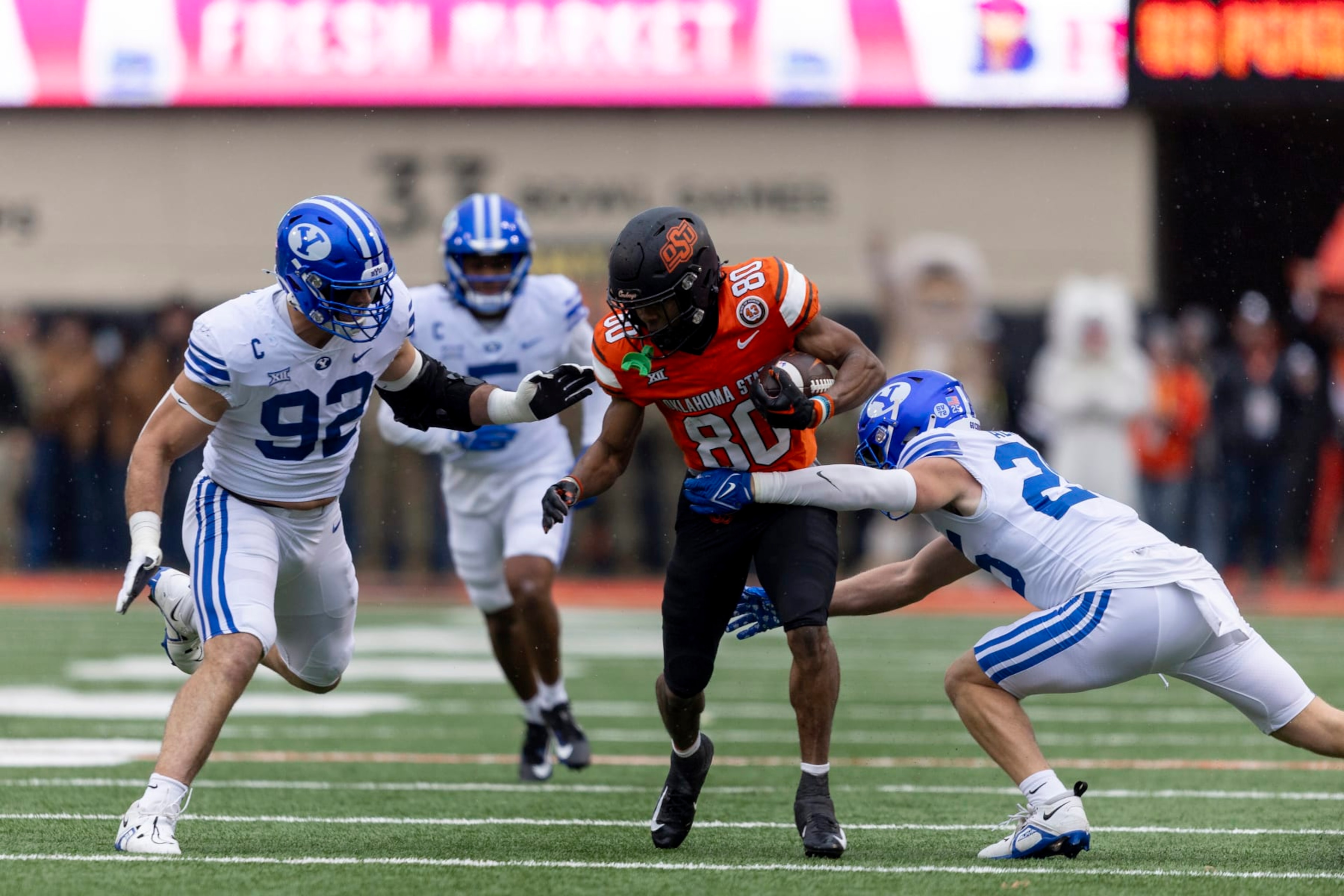 BYU safety Talan Alfrey (25) and defensive end Tyler Batty (92) tackle Oklahoma State wide receiver Brennan Presley (80) in the first half of an NCAA college football game Saturday, Nov. 25, 2023, in Stillwater, Okla. (AP Photo/Mitch Alcala)