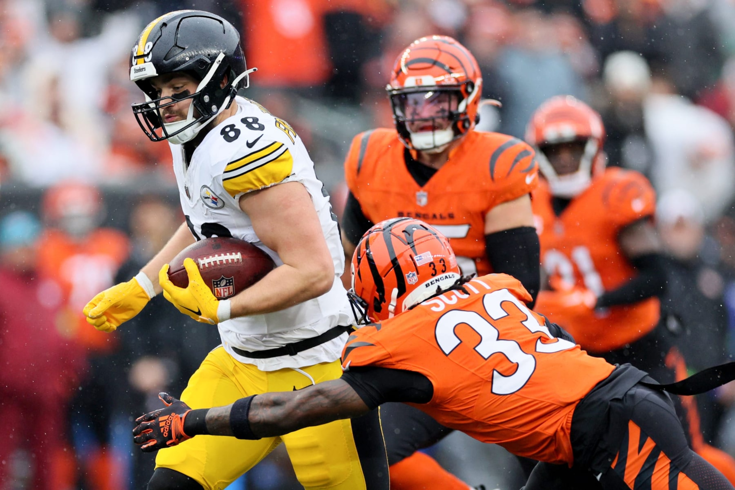 CINCINNATI, OHIO - NOVEMBER 26: Pat Freiermuth #88 of the Pittsburgh Steelers runs with the ball as Nick Scott #33 of the Cincinnati Bengals looks to make a tackle during the first quarter at Paycor Stadium on November 26, 2023 in Cincinnati, Ohio. (Photo by Andy Lyons/Getty Images)