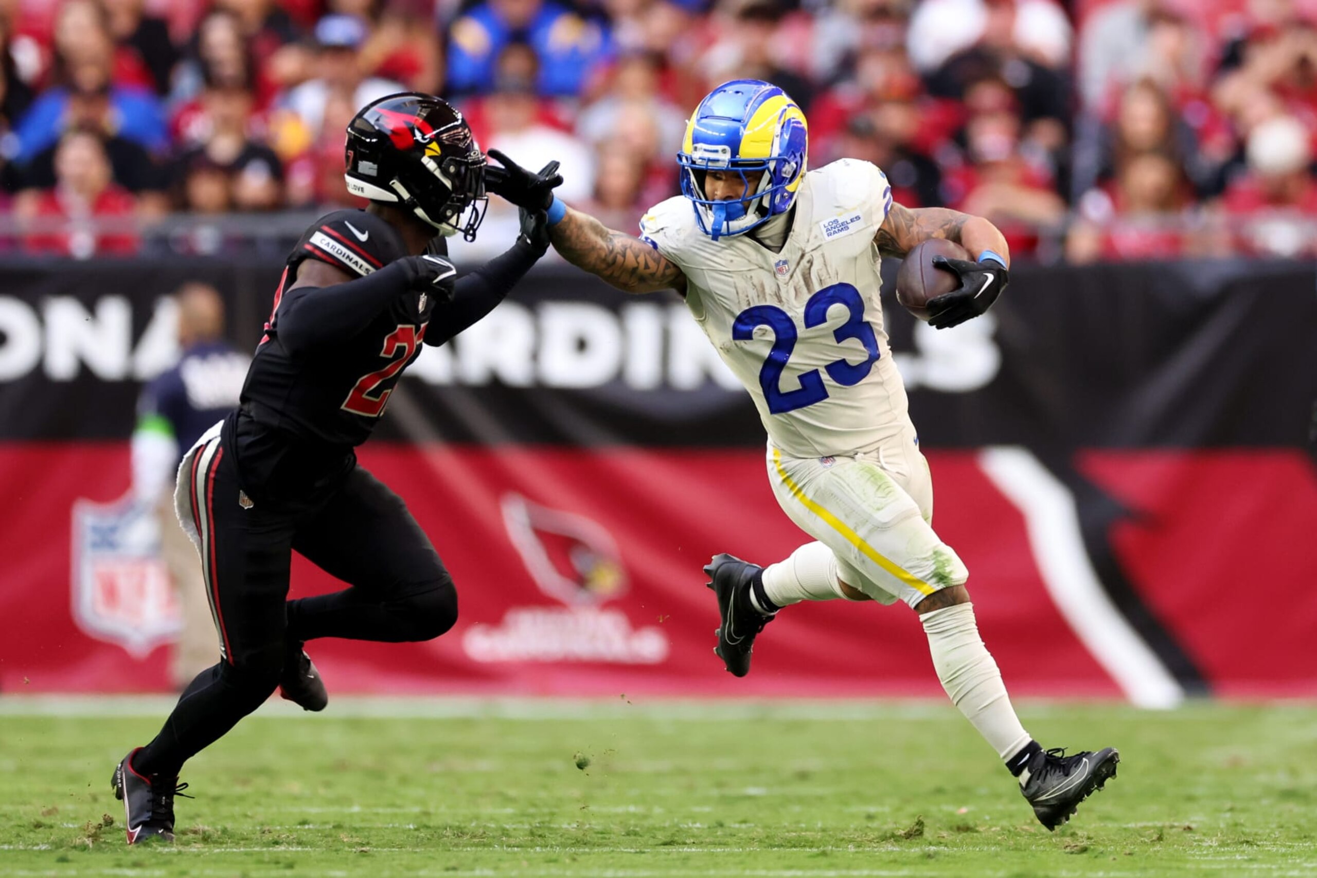GLENDALE, ARIZONA - NOVEMBER 26: Kyren Williams #23 of the Los Angeles Rams stiff arms Divaad Wilson #27 of the Arizona Cardinals during the second quarter at State Farm Stadium on November 26, 2023 in Glendale, Arizona. (Photo by Christian Petersen/Getty Images)