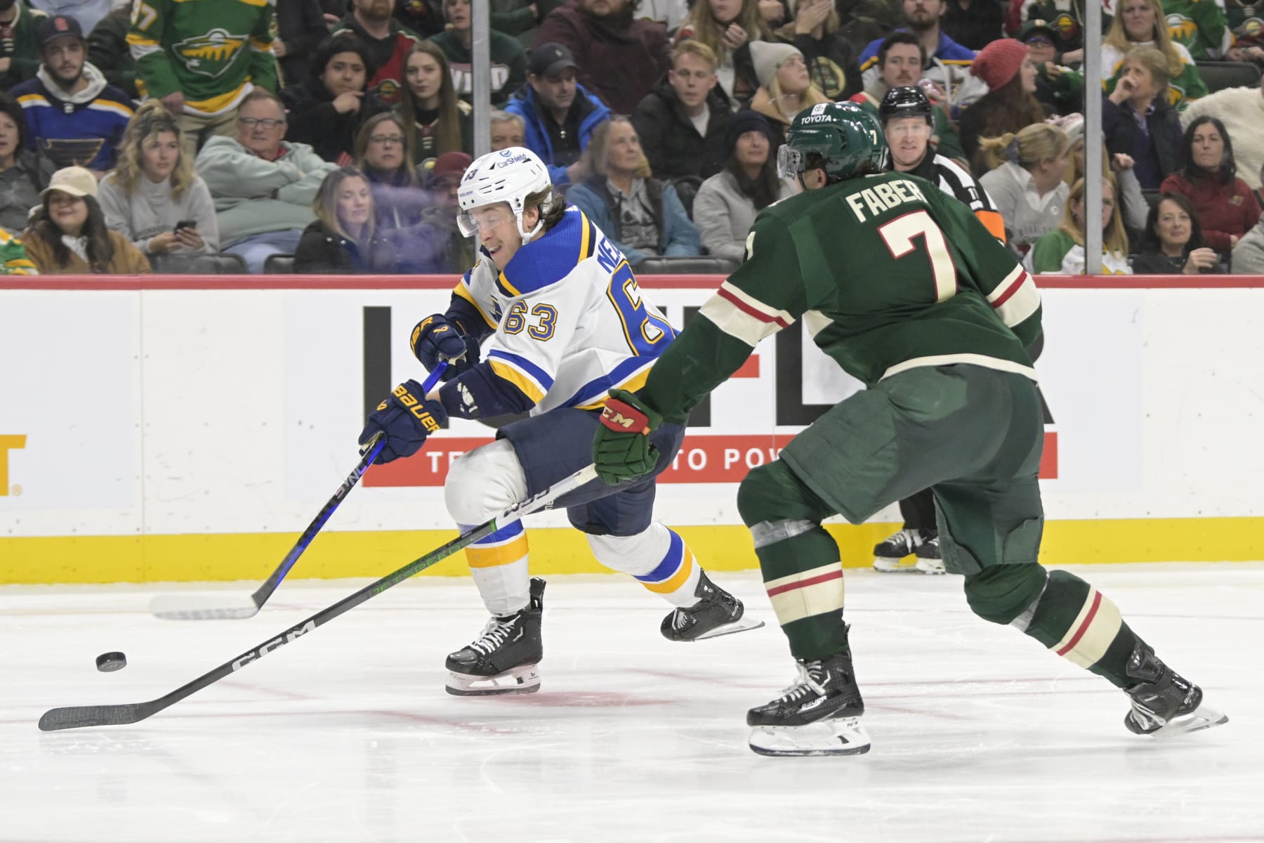 ST. PAUL, MN - NOVEMBER 28: St. Louis Blues forward Jake Neighbours (63) takes a shot as Minnesota Wild defenseman Brock Faber (7) defends during an NHL game between the Minnesota Wild and St. Louis Blues on November 28, 2023, at Xcel Energy Center in St. Paul, MN.(Photo by Nick Wosika/Icon Sportswire via Getty Images)