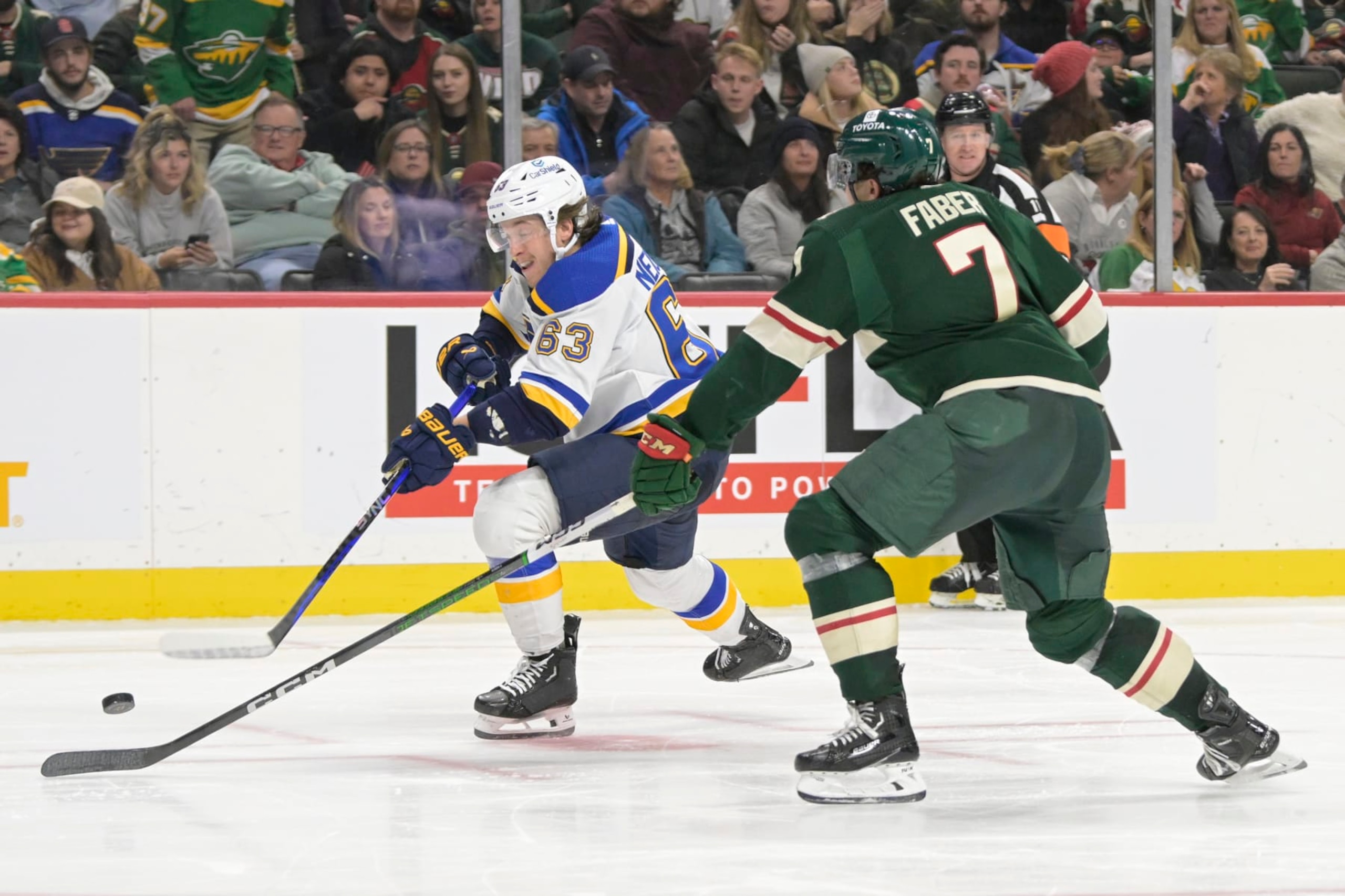ST. PAUL, MN - NOVEMBER 28: St. Louis Blues forward Jake Neighbours (63) takes a shot as Minnesota Wild defenseman Brock Faber (7) defends during an NHL game between the Minnesota Wild and St. Louis Blues on November 28, 2023, at Xcel Energy Center in St. Paul, MN.(Photo by Nick Wosika/Icon Sportswire via Getty Images)