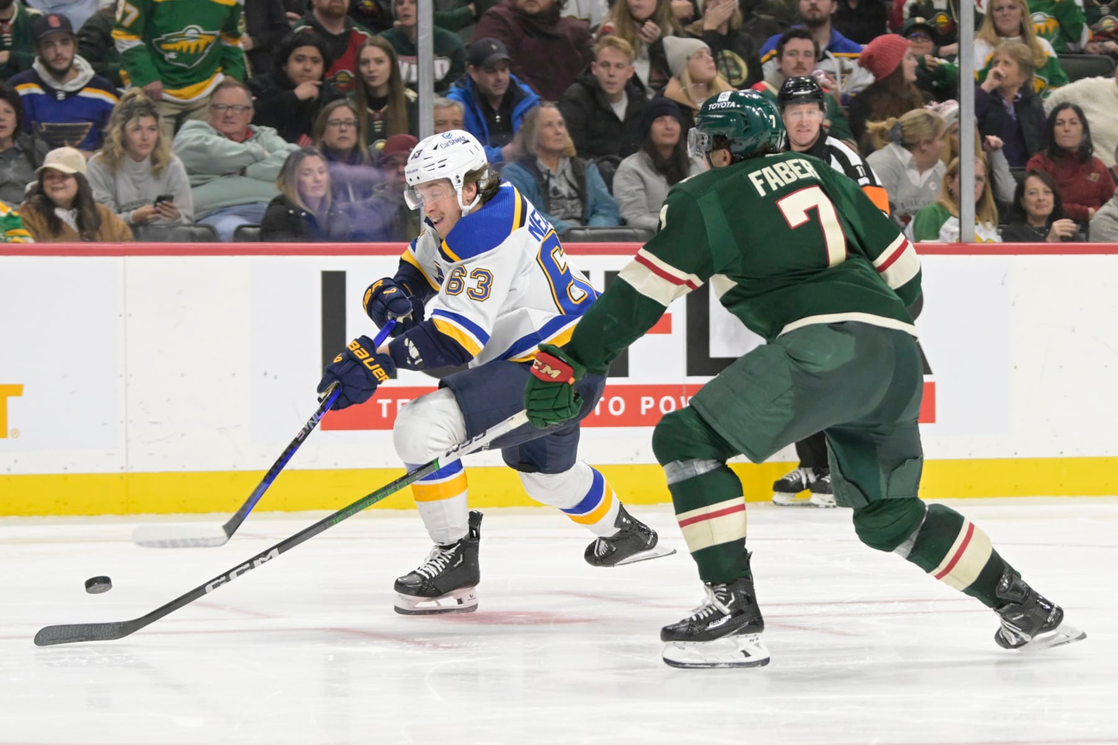 ST. PAUL, MN - NOVEMBER 28: St. Louis Blues forward Jake Neighbours (63) takes a shot as Minnesota Wild defenseman Brock Faber (7) defends during an NHL game between the Minnesota Wild and St. Louis Blues on November 28, 2023, at Xcel Energy Center in St. Paul, MN.(Photo by Nick Wosika/Icon Sportswire via Getty Images)