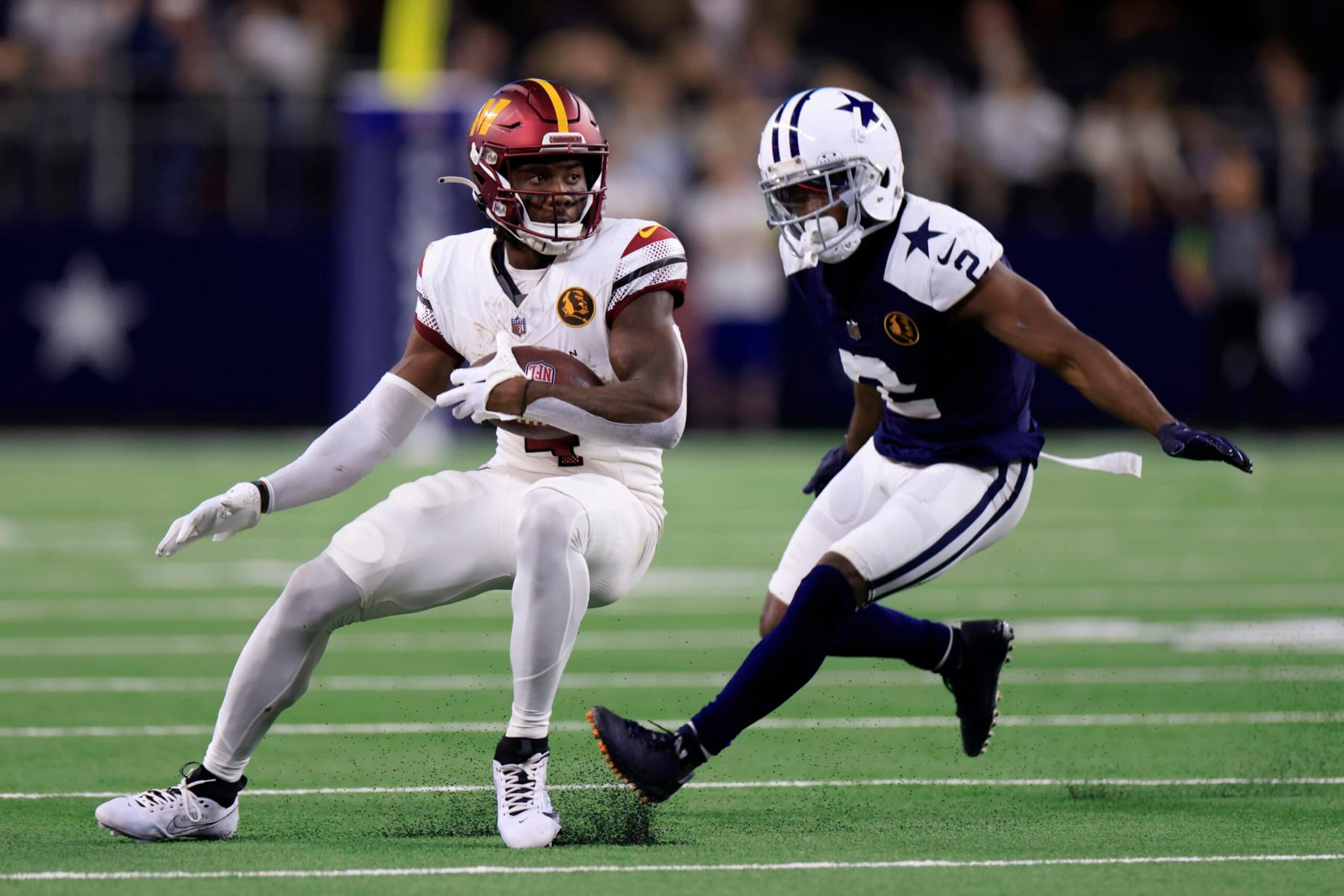 ARLINGTON, TEXAS - NOVEMBER 23: Curtis Samuel #4 of the Washington Commanders runs the ball while defended by Jourdan Lewis #2 of the Dallas Cowboys during the third quarter at AT&T Stadium on November 23, 2023 in Arlington, Texas. (Photo by Ron Jenkins/Getty Images)