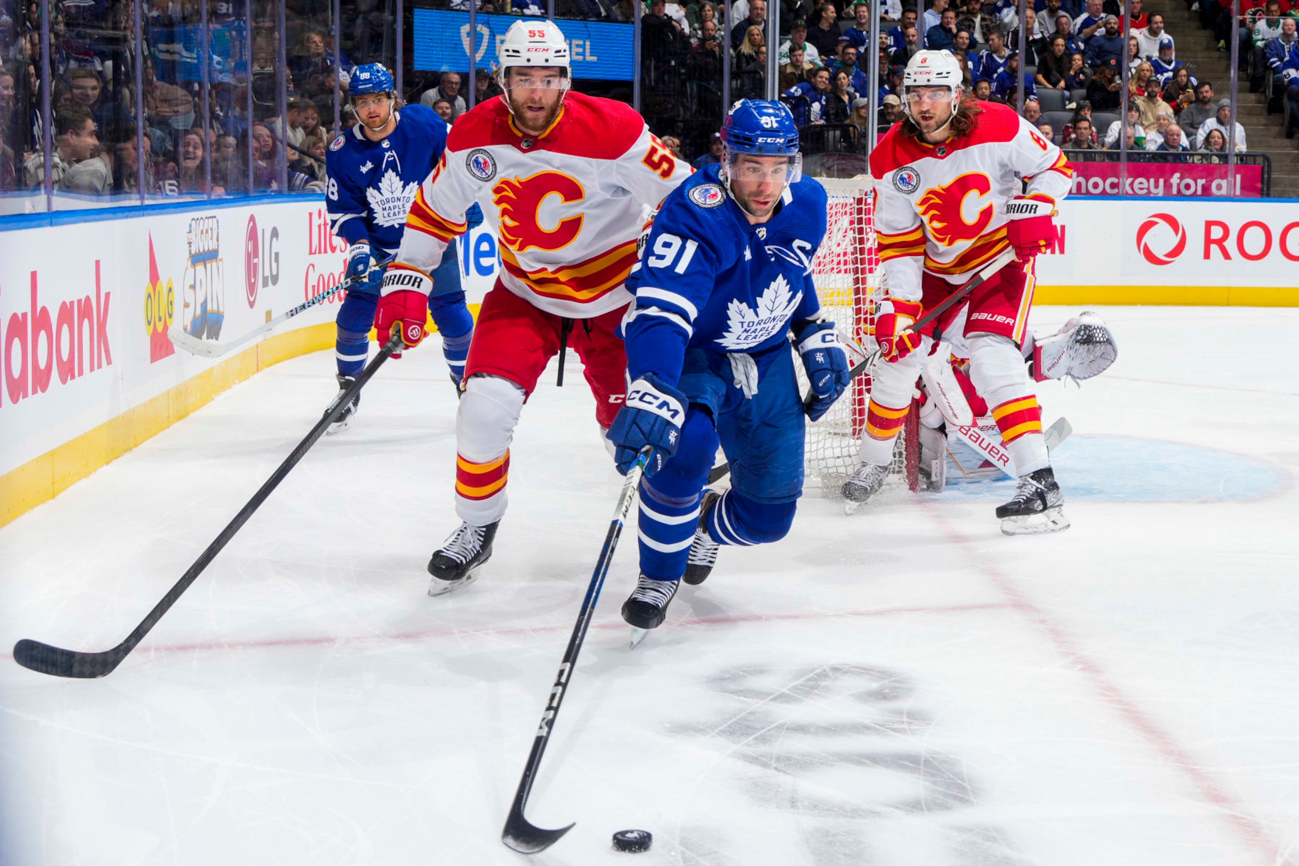 TORONTO, ON - NOVEMBER 10: John Tavares #91 of the Toronto Maple Leafs plays the puck agaistn Noah Hanifin #55 of the Calgary Flames during the first period at the Scotiabank Arena on November 10, 2023 in Toronto, Ontario, Canada. (Photo by Mark Blinch/NHLI via Getty Images)