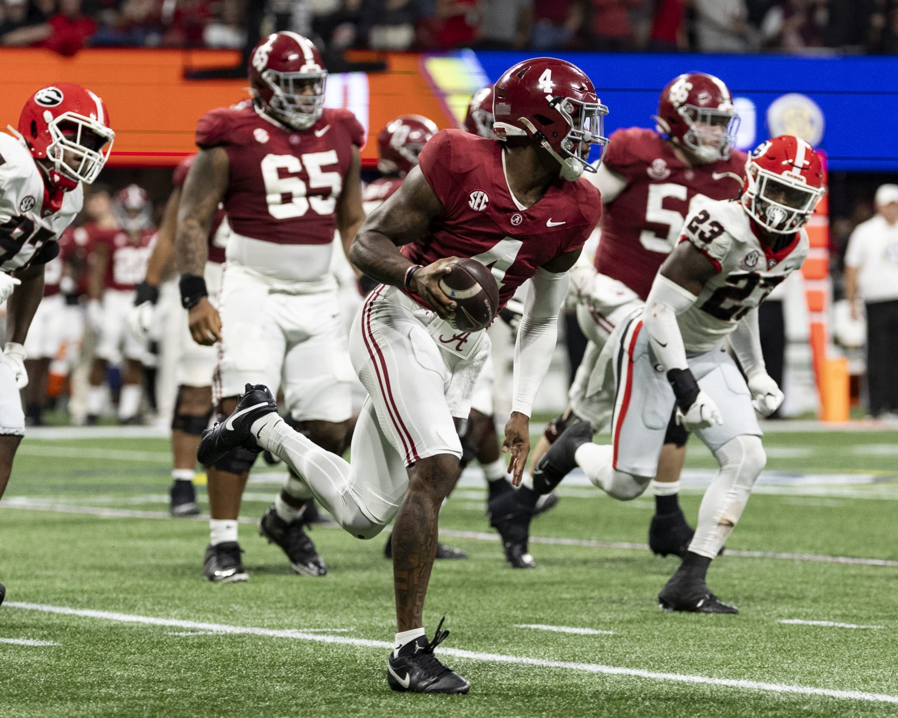 ATLANTA, GEORGIA - DECEMBER 2: Jalen Milroe #4 of the Alabama Crimson Tide avoids the Georgia pass rush during a game between University of Georgia and University of Alabama at Mercedes-Benz Stadium on December 2, 2023 in Atlanta, Georgia. (Photo by Steve Limentani/ISI Photos/Getty Images)