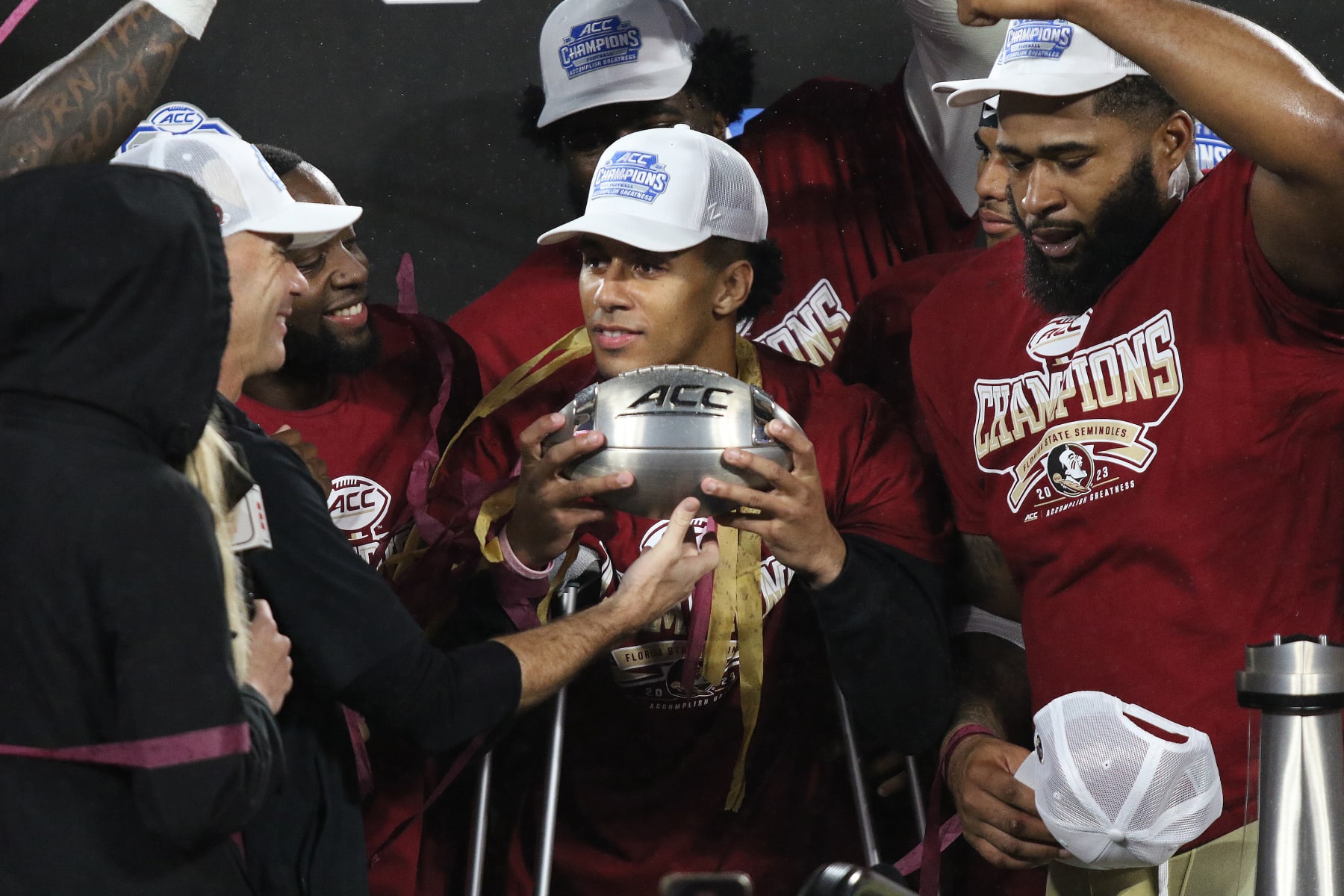 CHARLOTTE, NC - DECEMBER 02: Florida State Seminoles quarterback Jordan Travis (13) a day after having surgery holds the football trophy with his teammates during the ACC Football Championship Game between the Louisville Cardinals and the Florida State Seminoles on December 2, 2023 at Bank of America Stadium in Charlotte, N.C. (Photo by John Byrum/Icon Sportswire via Getty Images)