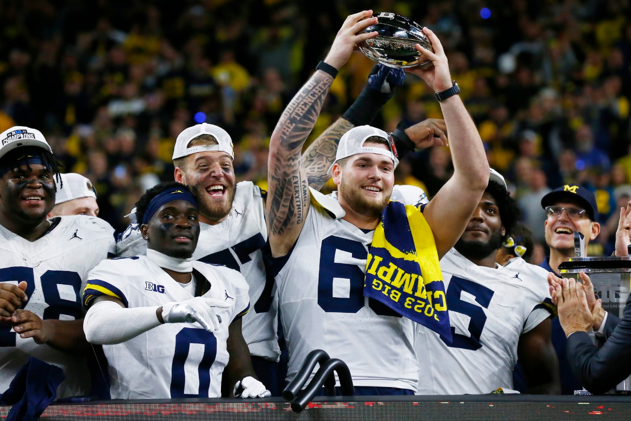 INDIANAPOLIS, IN - DECEMBER 02: Michigan Wolverines offensive lineman Zak Zinter (65) raises the B1G Championship trophy after Michigan wins the Big Ten Championship Game between the Michigan Wolverines and the Iowa Hawkeyes on December 02, 2023 at Lucas Oil Stadium in Indianapolis,IN.  (Photo by Jeffrey Brown/Icon Sportswire via Getty Images)