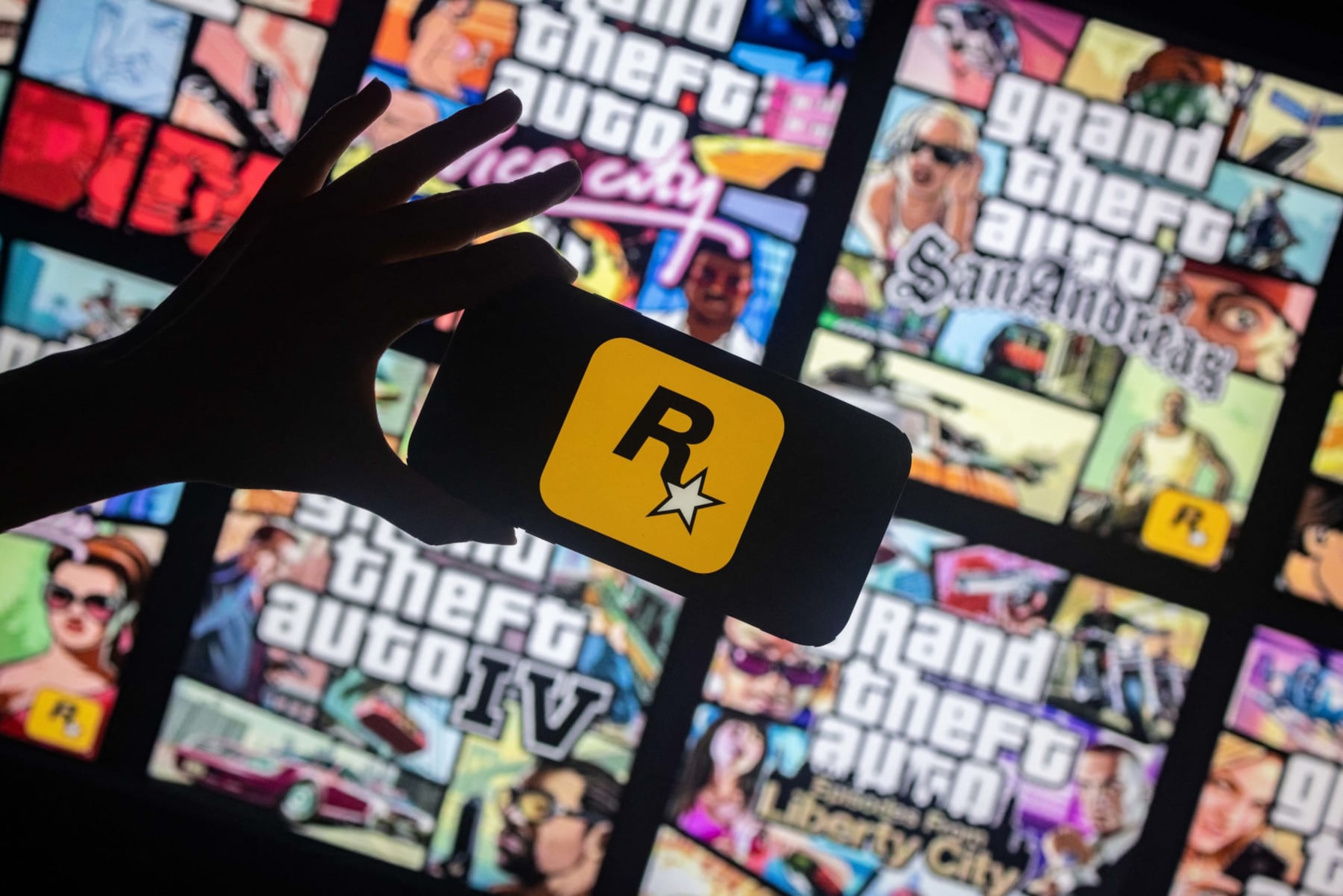 This illusttation shows a logo of Rockstar Games on a smartphone screen and covers of video game series Grand Theft Auto (GTA) on a TV screen in New York, November 27, 2023. Rockstar Games, the studio behind the blockbuster Grand Theft Auto series, has said it will release the trailer for the next instalment, GTA VI, in December, setting the gaming world abuzz. (Photo by Yuki IWAMURA / AFP) (Photo by YUKI IWAMURA/AFP via Getty Images) This illusttation shows a logo of Rockstar Games on a smartphone screen and covers of video game series Grand Theft Auto (GTA) on a TV screen in New York, November 27, 2023. Rockstar Games, the studio behind the blockbuster Grand Theft Auto series, has said it will release the trailer for the next instalment, GTA VI, in December, setting the gaming world abuzz. (Photo by Yuki IWAMURA / AFP) (Photo by YUKI IWAMURA/AFP via Getty Images)
