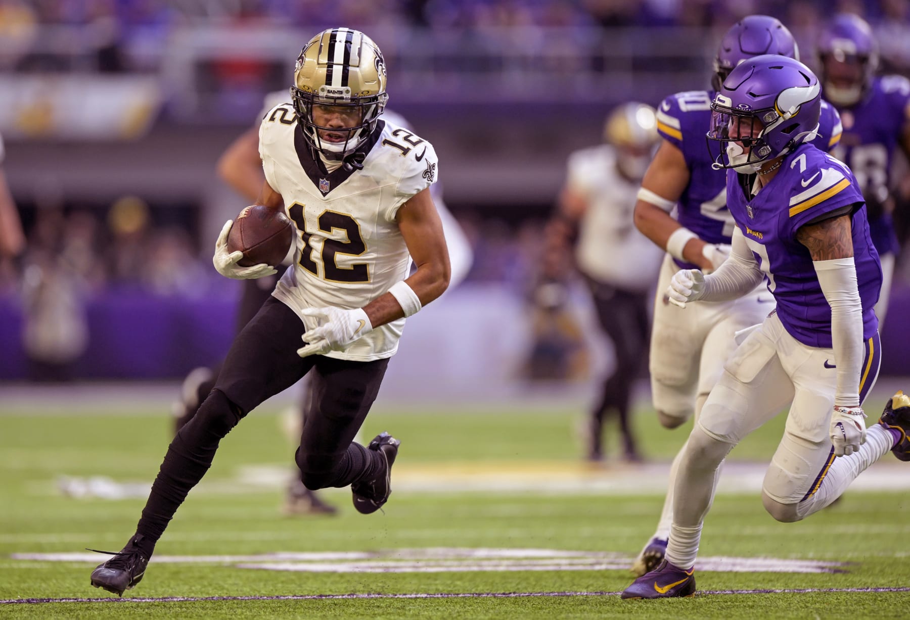 MINNEAPOLIS, MN - NOVEMBER 12: New Orleans Saints wide receiver Chris Olave (12) runs with the ball as Minnesota Vikings defensive back Byron Murphy (7) gives chase during the fourth quarter of an NFL game between the Minnesota Vikings and New Orleans Saints on November 12, 2023, at U.S. Bank Stadium in Minneapolis, MN. (Photo by Nick Wosika/Icon Sportswire via Getty Images)