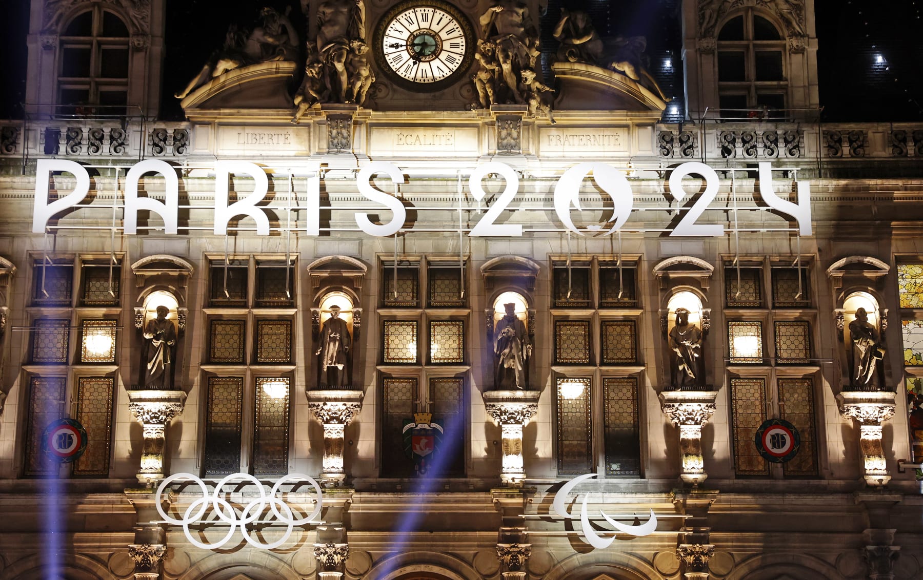 PARIS, FRANCE - NOVEMBER 28: The logo, Paris 2024 representing the Olympic Games, several months prior to the start of the Paris 2024 Olympic and Paralympic Games is displayed on the illumined facade of Paris town hall on November 28, 2023 in Paris, France. France will host the Olympic Games on Friday July 26 to Sunday August 11, 2024. (Photo by Chesnot/Getty Images)