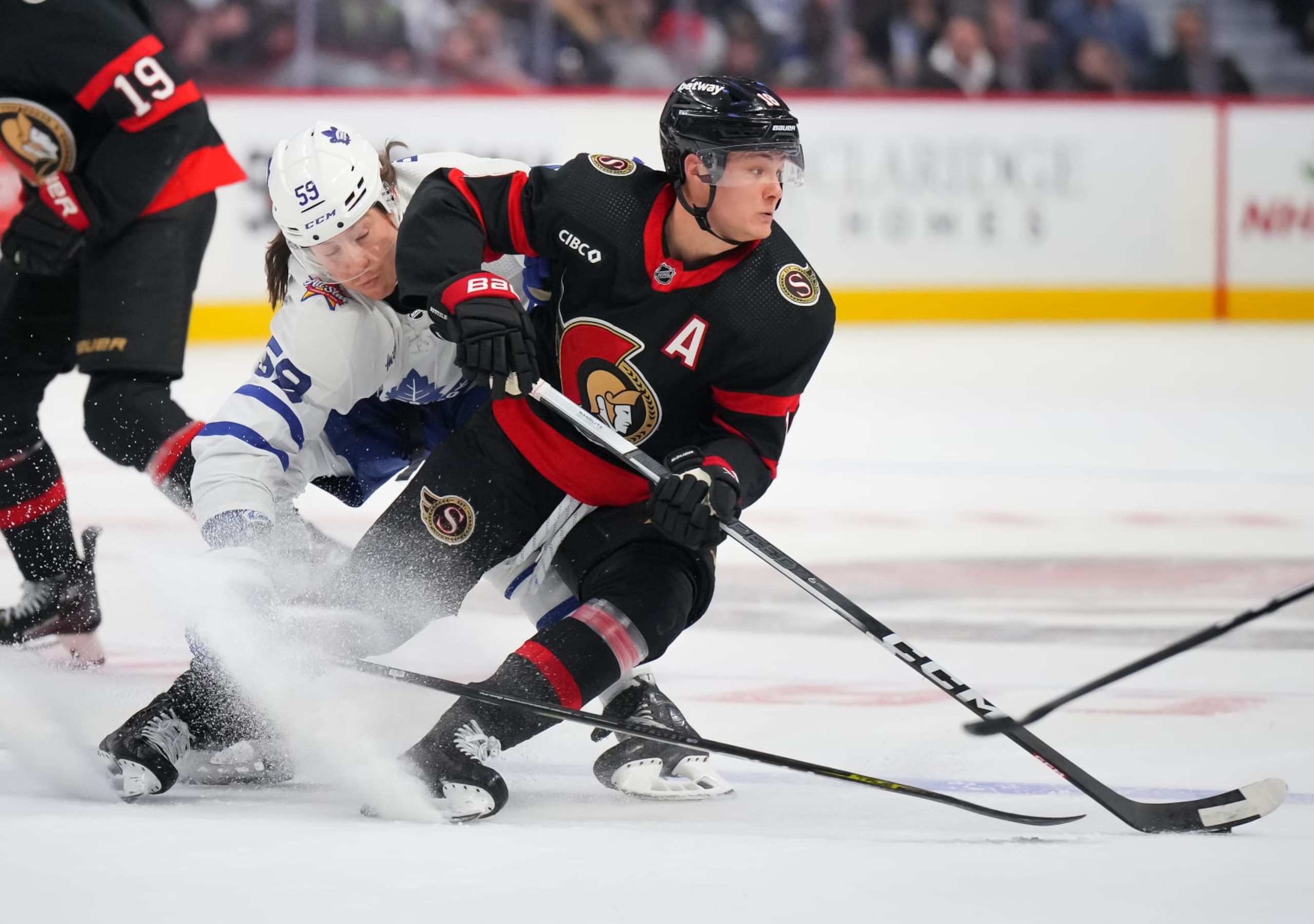 OTTAWA, CANADA - DECEMBER 7: Tim Stützle #18 of the Ottawa Senators controls the puck against Tyler Bertuzzi #59 of the Toronto Maple Leafs during the first period at Canadian Tire Centre on December 7, 2023 in Ottawa, Ontario, Canada.  (Photo by André Ringuette/NHLI via Getty Images)