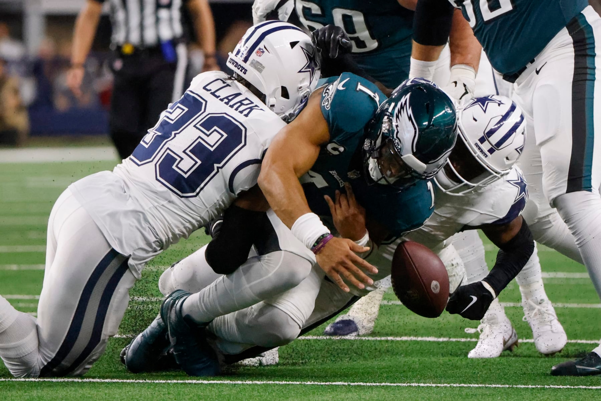 Dallas Cowboys safety Donovan Wilson, right, forces a fumble by Philadelphia Eagles quarterback Jalen Hurts, center, as teammate Damone Clark (33) helps apply pressure during the first half of an NFL football game, Sunday, Dec. 10, 2023, in Arlington, Texas. The Cowboys recovered the ball on the play. (AP Photo/Michael Ainsworth)
