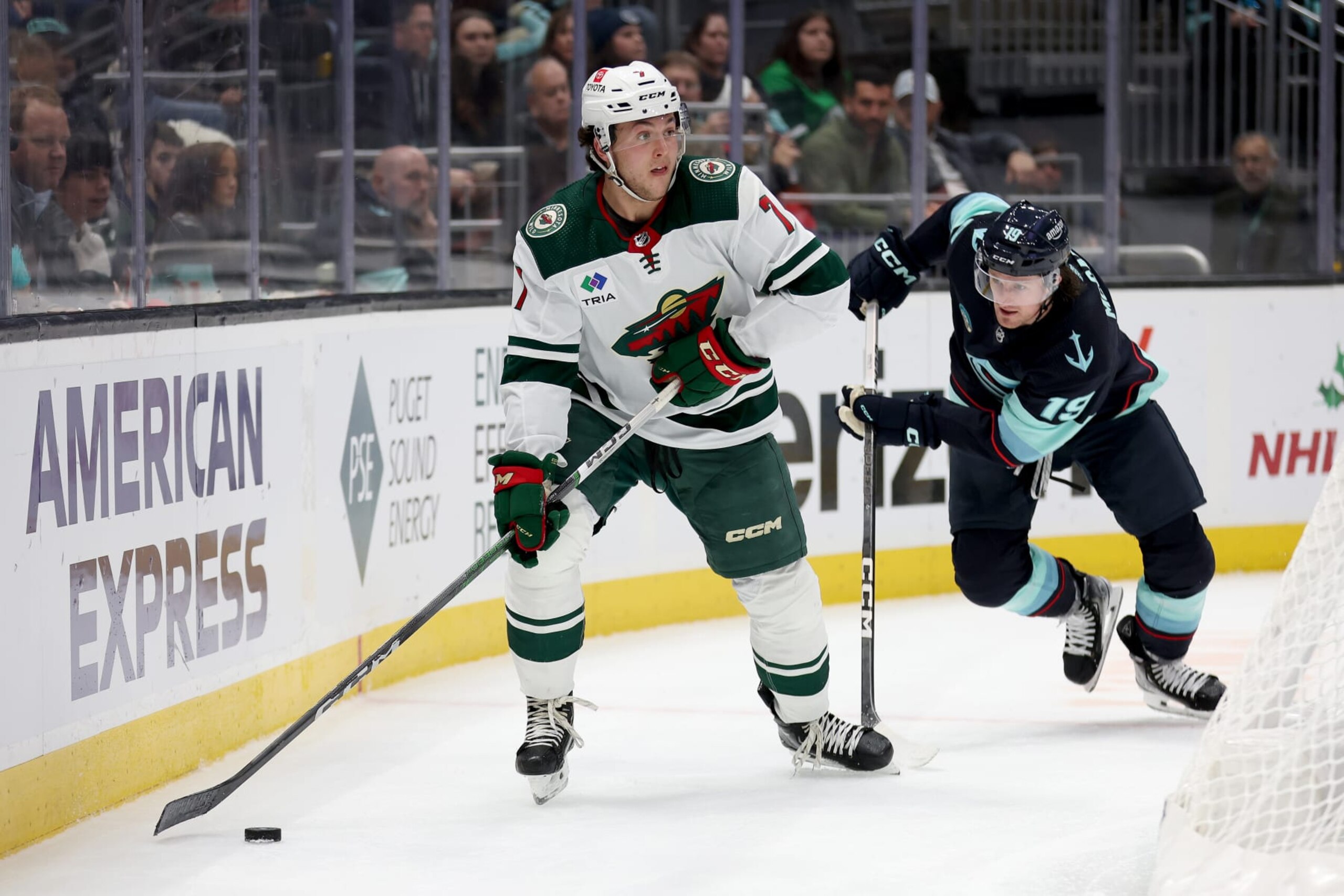 SEATTLE, WASHINGTON - DECEMBER 10: Brock Faber #7 of the Minnesota Wild skates against Jared McCann #19 of the Seattle Kraken during the second period at Climate Pledge Arena on December 10, 2023 in Seattle, Washington. (Photo by Steph Chambers/Getty Images)