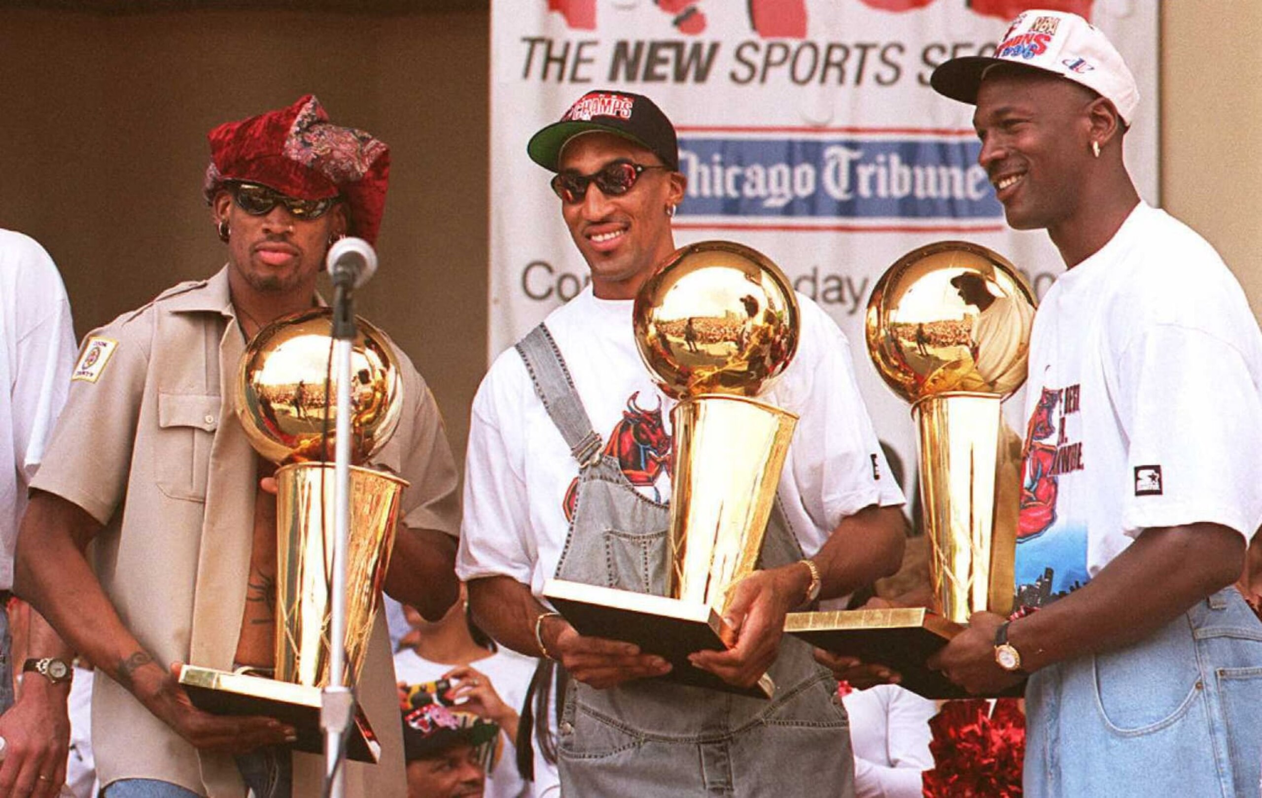 CHICAGO, IL - JUNE 18:  Chicago Bulls players Dennis Rodman (L), Scottie Pippen (C) and Michael Jordan (R) hold three of the team's four recent Larry O'Brien trophies 18 June at a rally for the team in Grant Park in Chicago.  Thousands of fans crowded into the park to see the NBA champions.  (Photo credit should read TIM ZIELENBACH/AFP via Getty Images)