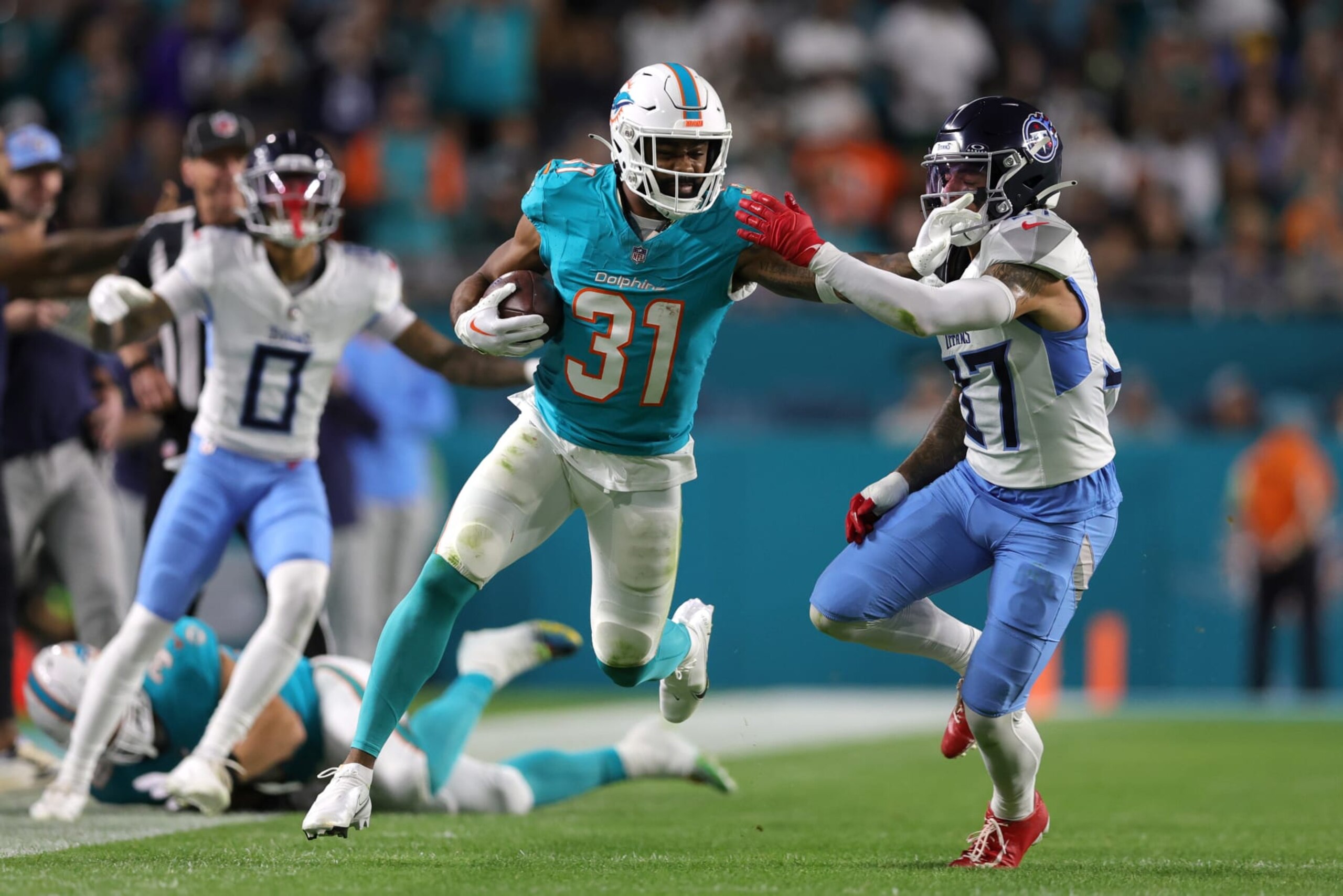 MIAMI GARDENS, FLORIDA - DECEMBER 11: Raheem Mostert #31 of the Miami Dolphins stiff arms Amani Hooker #37 of the Tennessee Titans in the first half at Hard Rock Stadium on December 11, 2023 in Miami Gardens, Florida. (Photo by Megan Briggs/Getty Images)