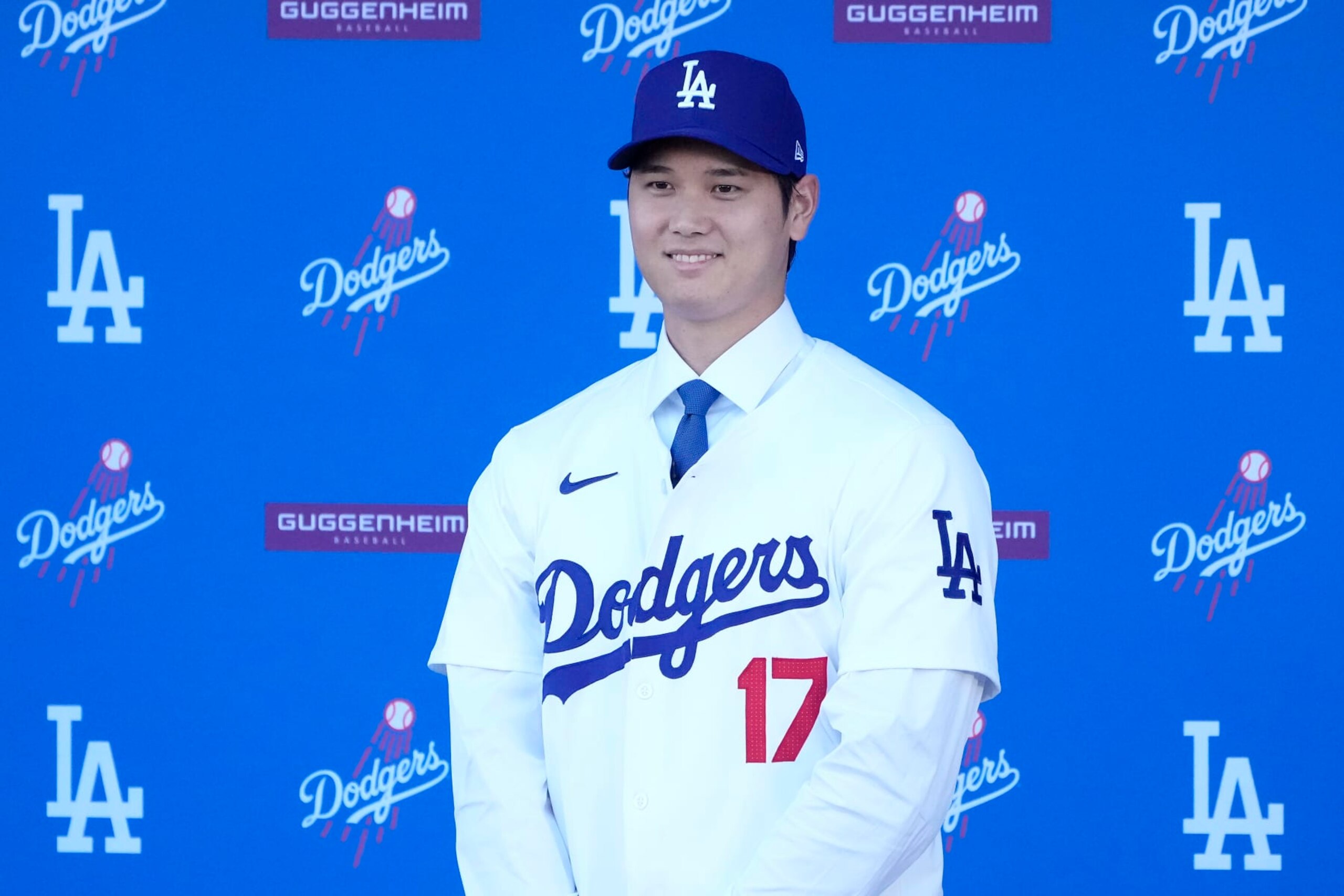 Los Angeles Dodgers' Shohei Ohtani smiles while wearing a jersey and baseball cap during a news conference at Dodger Stadium Thursday, Dec. 14, 2023, in Los Angeles. (AP Photo/Marcio Jose Sanchez)