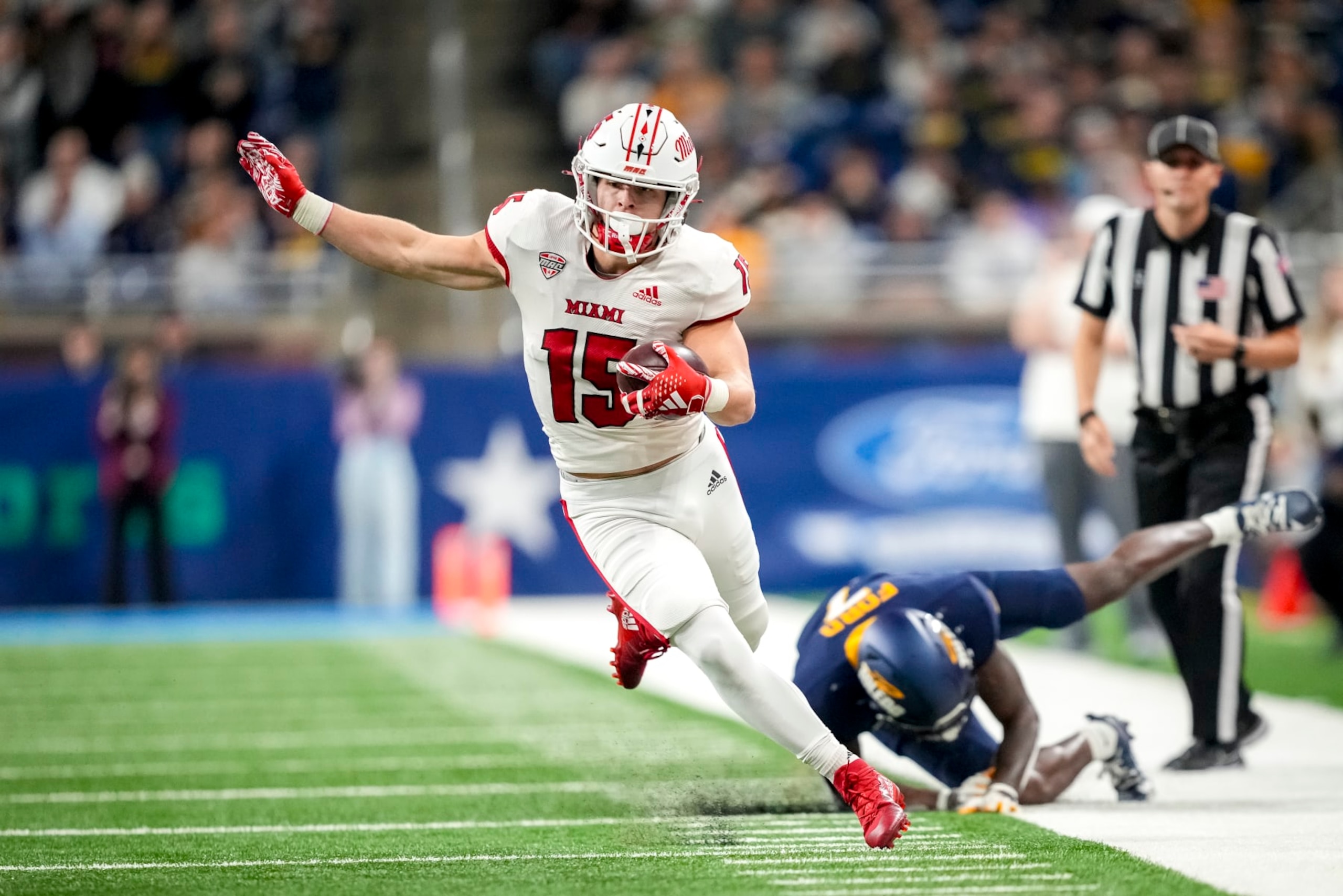 DETROIT, MICHIGAN - DECEMBER 02: Cade McDonald #15 of the Miami (Oh) Redhawks runs the ball against Zachary Ford #7 of the Toledo Rockets during the first quarter of the MAC Championship at Ford Field on December 02, 2023 in Detroit, Michigan. (Photo by Nic Antaya/Getty Images) DETROIT, MICHIGAN - DECEMBER 02: Cade McDonald #15 of the Miami (Oh) Redhawks runs the ball against Zachary Ford #7 of the Toledo Rockets during the first quarter of the MAC Championship at Ford Field on December 02, 2023 in Detroit, Michigan. (Photo by Nic Antaya/Getty Images)