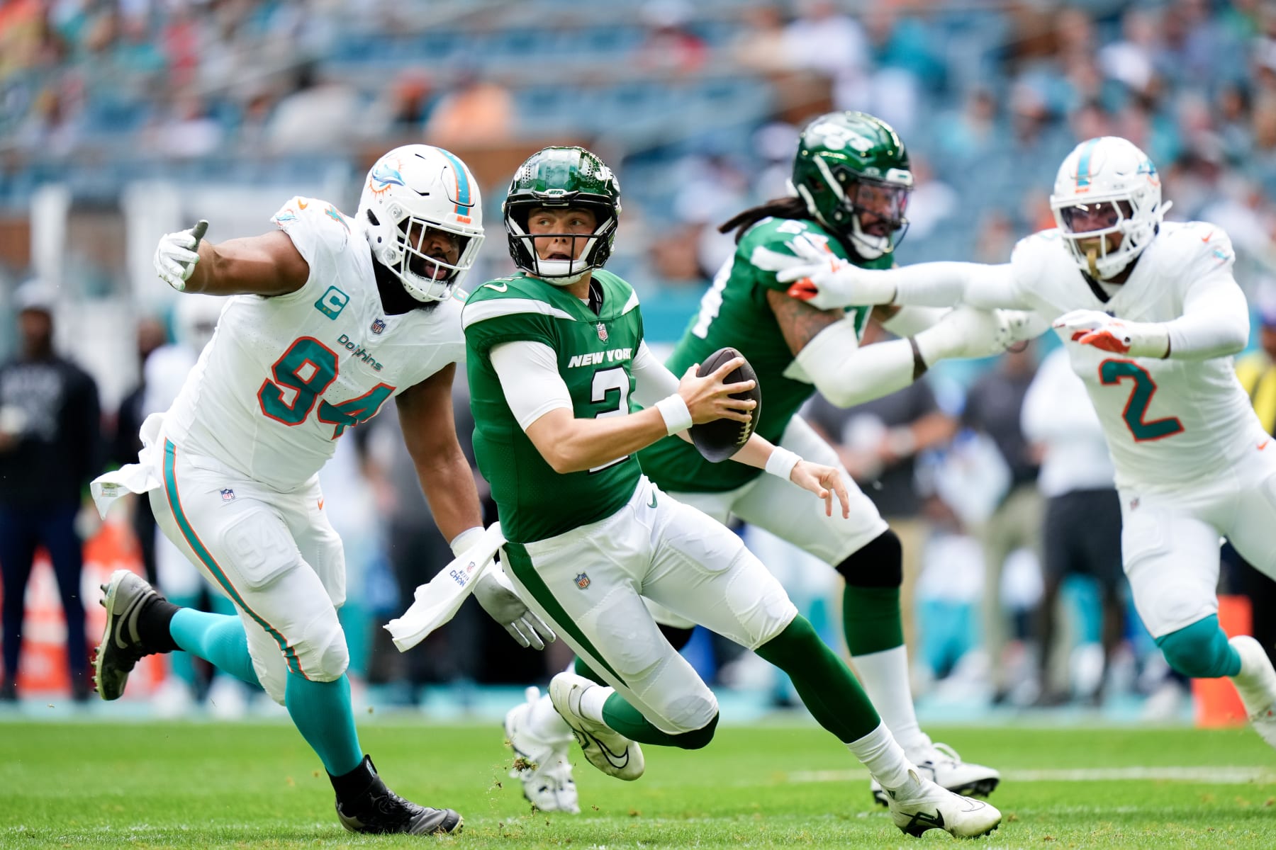 MIAMI GARDENS, FLORIDA - DECEMBER 17: Zach Wilson #2 of the New York Jets scrambles as Christian Wilkins #94 of the Miami Dolphins looks to make a tackle during the first quarter at Hard Rock Stadium on December 17, 2023 in Miami Gardens, Florida. (Photo by Rich Storry/Getty Images)