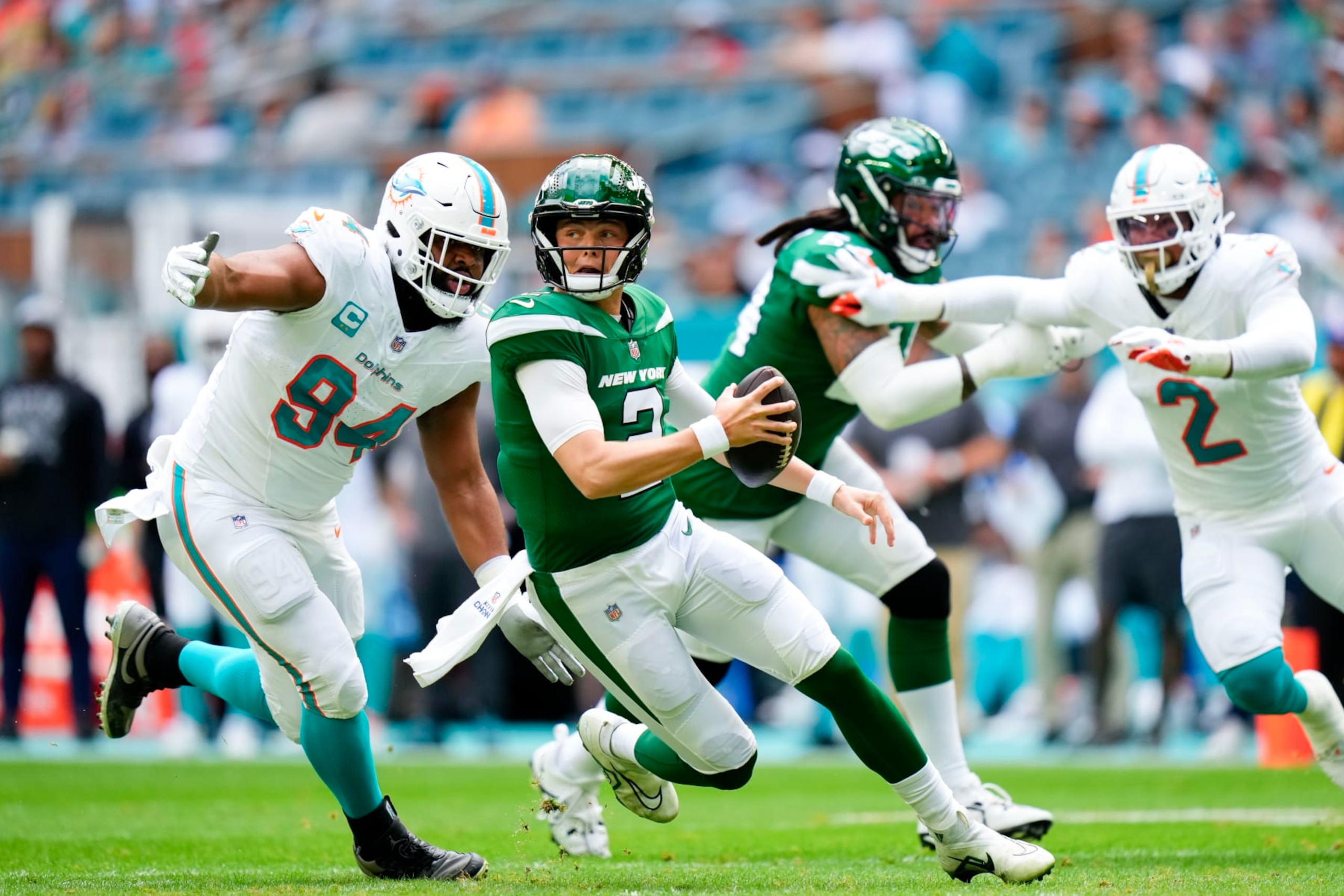 MIAMI GARDENS, FLORIDA - DECEMBER 17: Zach Wilson #2 of the New York Jets scrambles as Christian Wilkins #94 of the Miami Dolphins looks to make a tackle during the first quarter at Hard Rock Stadium on December 17, 2023 in Miami Gardens, Florida. (Photo by Rich Storry/Getty Images)