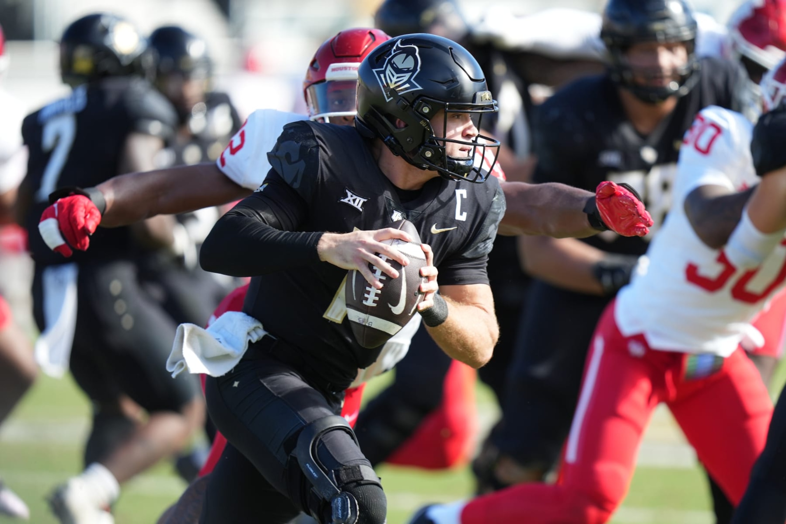 ORLANDO, FL - NOVEMBER 25: UCF Knights quarterback John Rhys Plumlee (10) rushes with he ball as Houston Cougars defensive lineman David Ugwoegbu (12) looks to make the tackle during the game between the Houston Cougars and the Central Florida (UCF) Knights on Saturday, November 25, 2023 at FBC Mortgage Stadium, Orlando, Fla. (Photo by Peter Joneleit/Icon Sportswire via Getty Images)