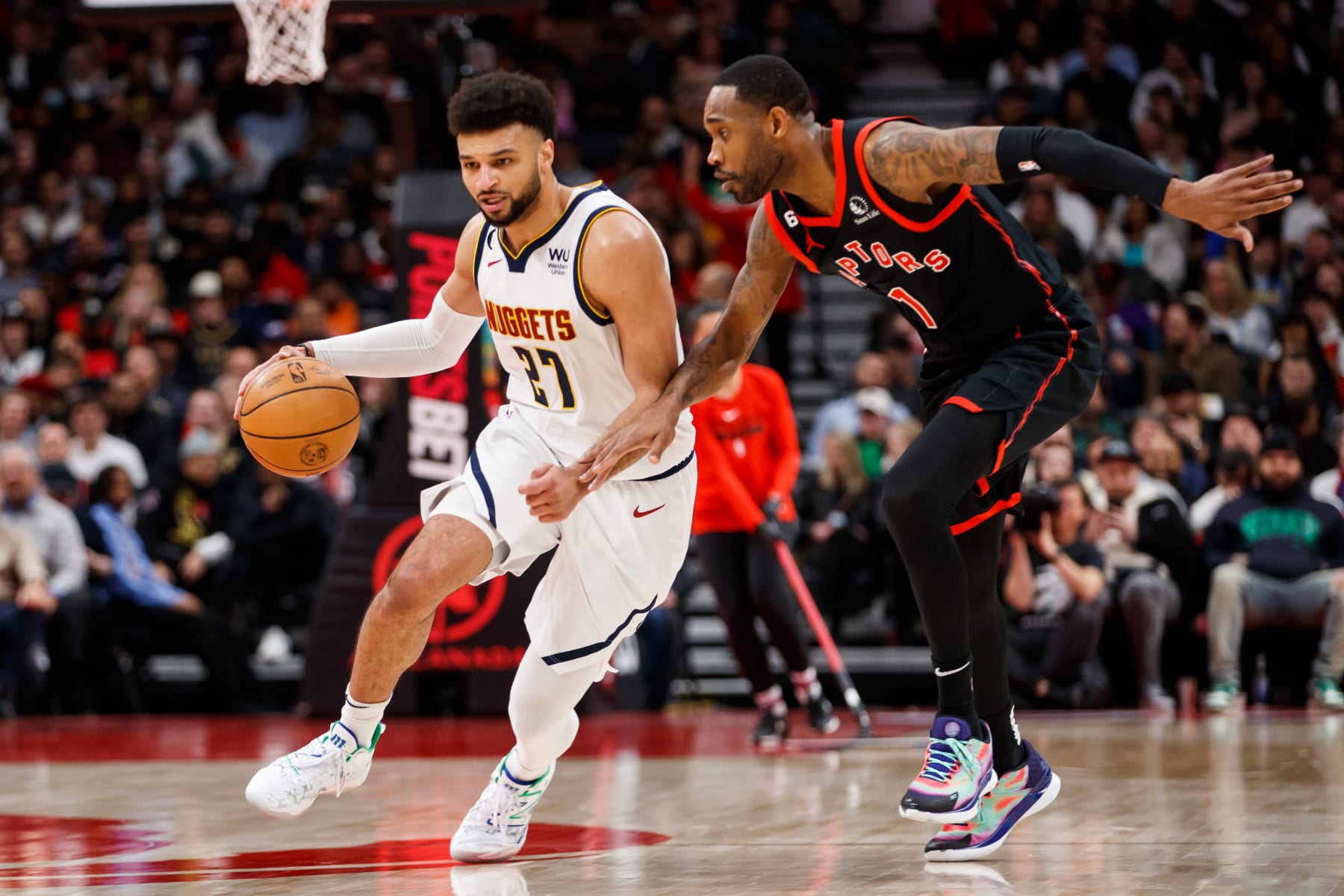 TORONTO, ON - MARCH 14: Jamal Murray #27 of the Denver Nuggets dribbles against Will Barton #1 of the Toronto Raptors during the first half of their NBA game 
at Scotiabank Arena on March 14, 2023 in Toronto, Canada. NOTE TO USER: User expressly acknowledges and agrees that, by downloading and or using this photograph, User is consenting to the terms and conditions of the Getty Images License Agreement. (Photo by Cole Burston/Getty Images)