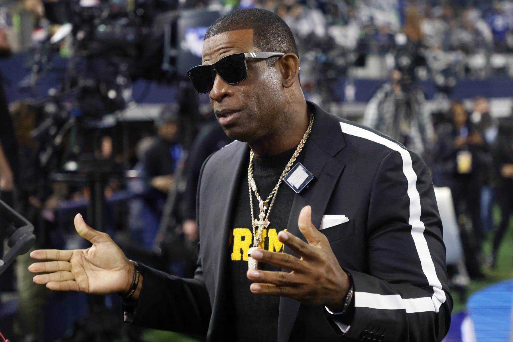 Colorado head football coach Deion Sanders talks with persons on the sideline before an NFL football game between the Seattle Seahawks and Dallas Cowboys in Arlington, Texas, Thursday, Nov. 30, 2023. (AP Photo/Michael Ainsworth)