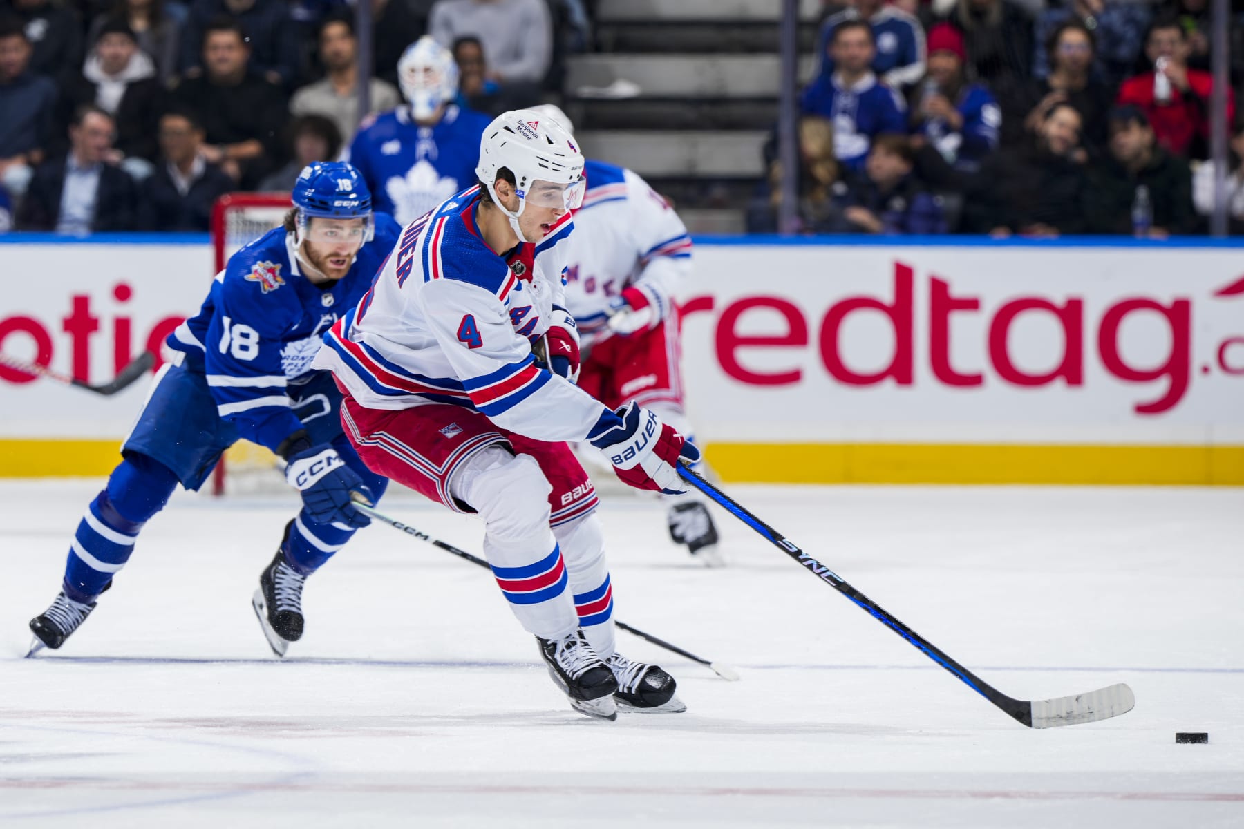 TORONTO, ON - DECEMBER 19: Braden Schneider #4 of the New York Rangers plays the puck against Noah Gregor #18 of the Toronto Maple Leafs during the first period at Scotiabank Arena on December 19, 2023 in Toronto, Ontario, Canada. (Photo by Mark Blinch/NHLI via Getty Images)