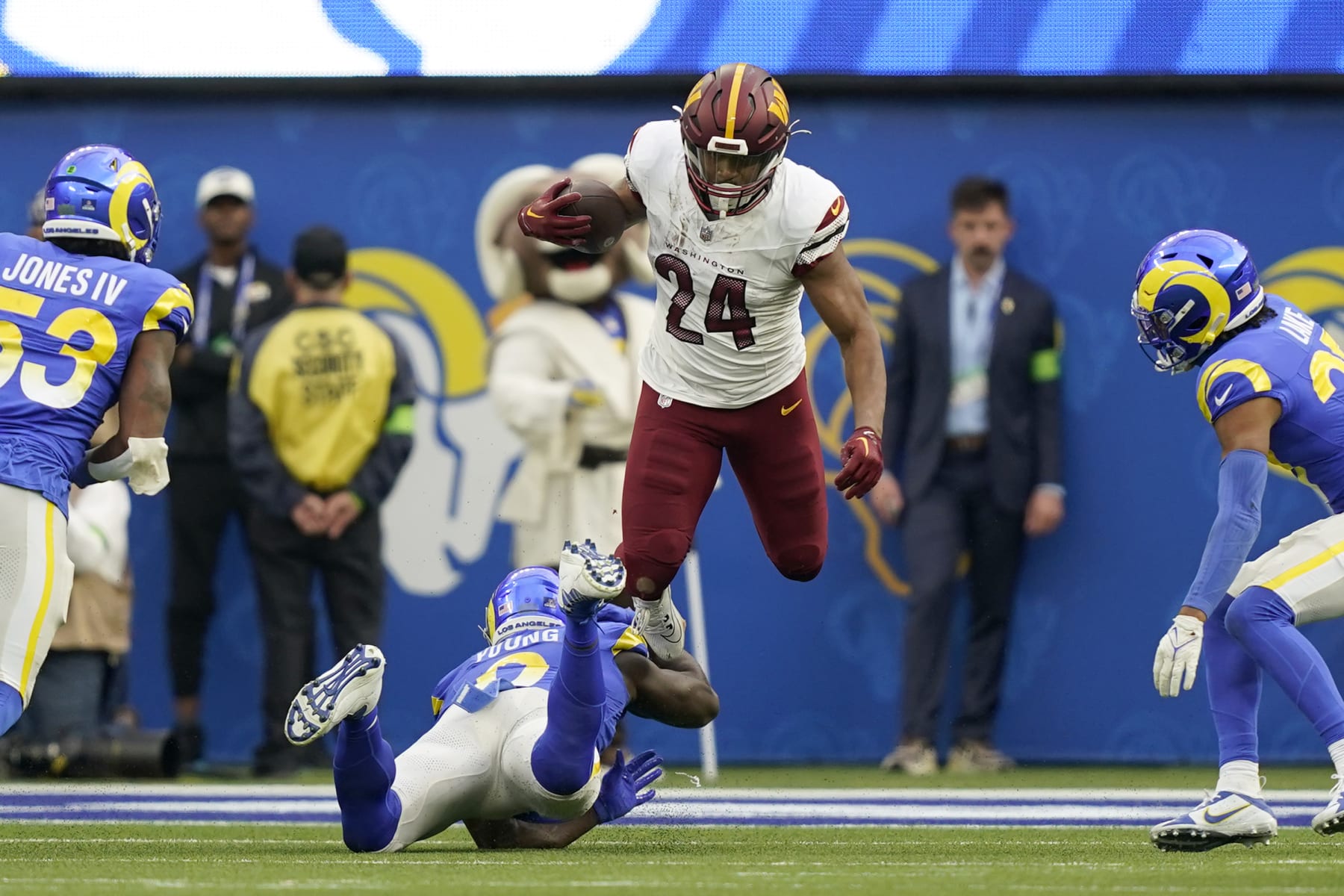 Washington Commanders running back Antonio Gibson (24) jumps over Los Angeles Rams linebacker Byron Young (0) during the first half of an NFL football game Sunday, Dec. 17, 2023, in Los Angeles. (AP Photo/Ryan Sun)