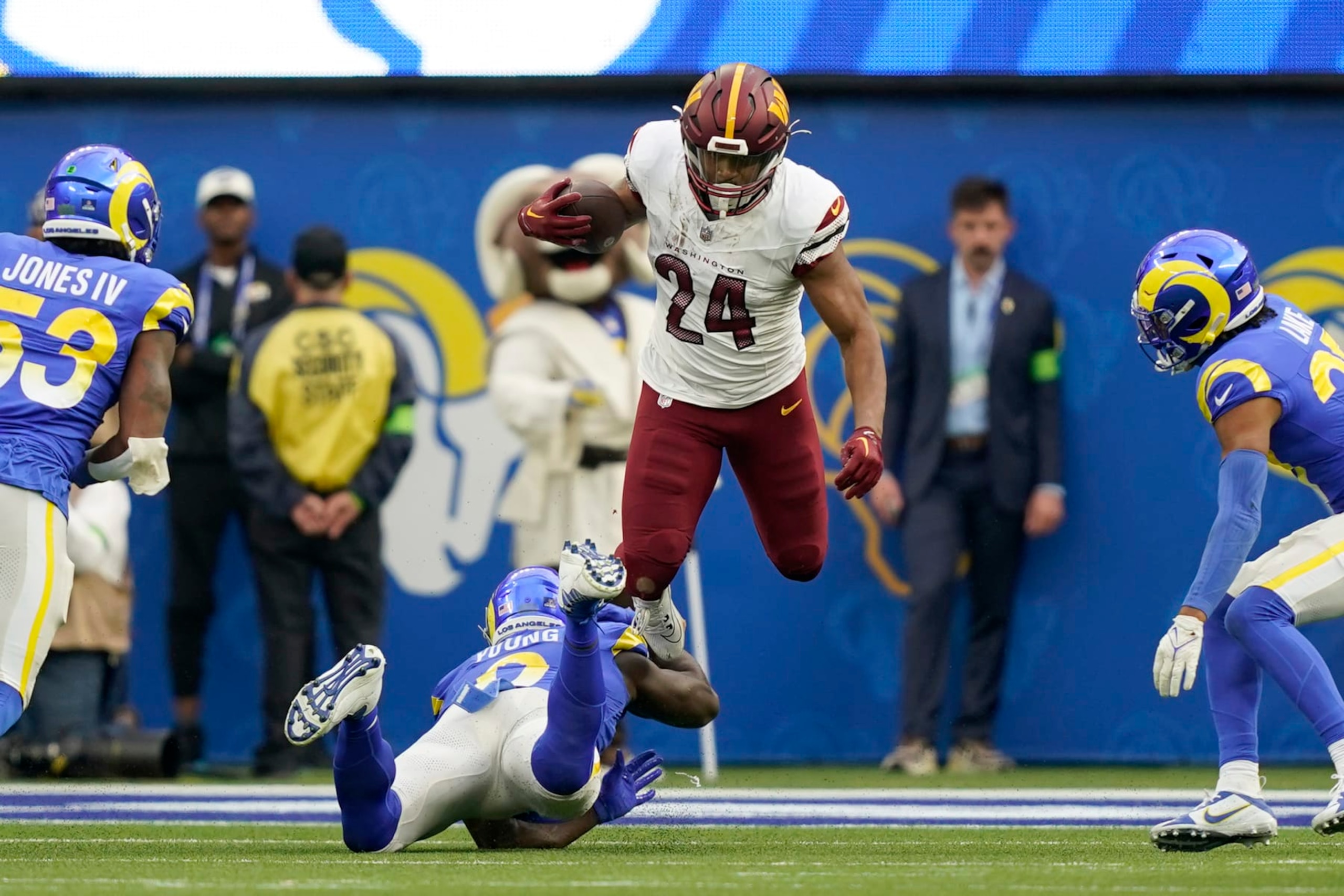 Washington Commanders running back Antonio Gibson (24) jumps over Los Angeles Rams linebacker Byron Young (0) during the first half of an NFL football game Sunday, Dec. 17, 2023, in Los Angeles. (AP Photo/Ryan Sun)