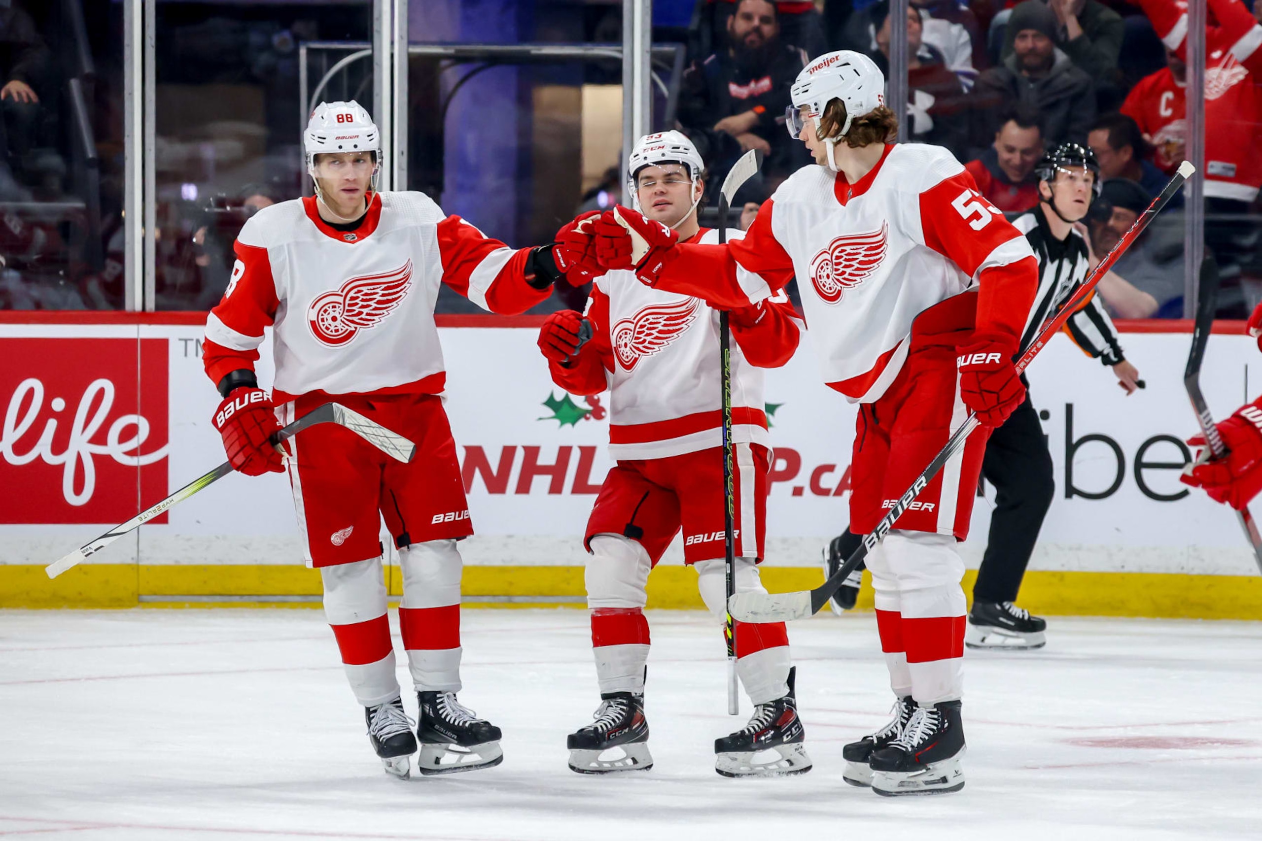 WINNIPEG, CANADA - DECEMBER 20: Patrick Kane #88, Alex DeBrincat #93 and Moritz Seider #53 of the Detroit Red Wings celebrate a third period goal against the Winnipeg Jets at the Canada Life Centre on December 20, 2023 in Winnipeg, Manitoba, Canada. (Photo by Jonathan Kozub/NHLI via Getty Images)