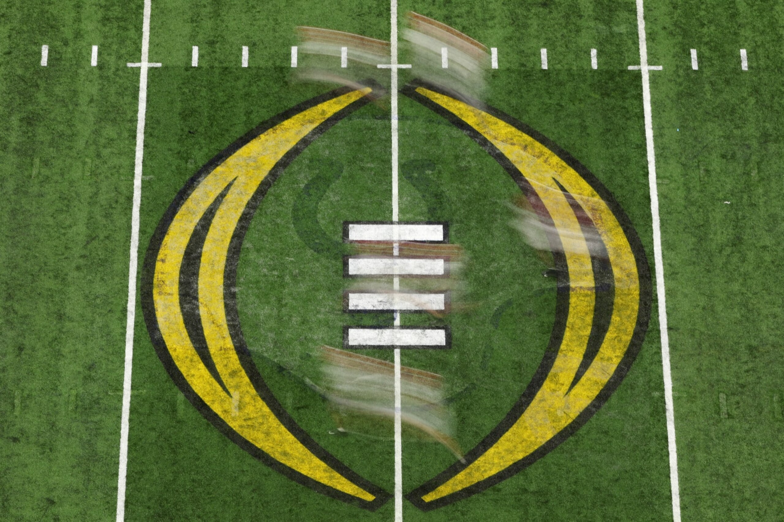 INDIANAPOLIS, INDIANA - JANUARY 10: Players run across the 2022 CFP National Championship logo on the field in the first quarter of the game between the Georgia Bulldogs and the Alabama Crimson Tide during the 2022 CFP National Championship Game at Lucas Oil Stadium on January 10, 2022 in Indianapolis, Indiana. (Photo by Dylan Buell/Getty Images)