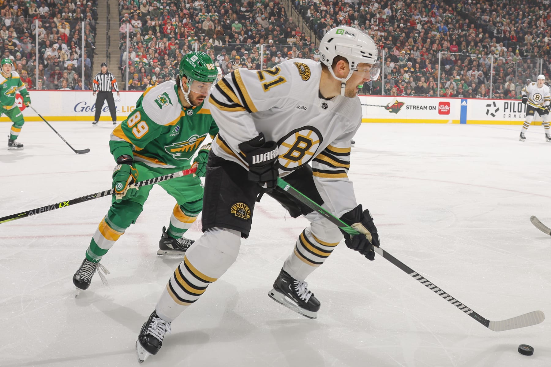 SAINT PAUL, MN - DECEMBER 23: James van Riemsdyk #21 of the Boston Bruins skates with the puck while Frederick Gaudreau #89 of the Minnesota Wild defends during the game at the Xcel Energy Center on December 23, 2023 in Saint Paul, Minnesota. (Photo by Bruce Kluckhohn/NHLI via Getty Images)